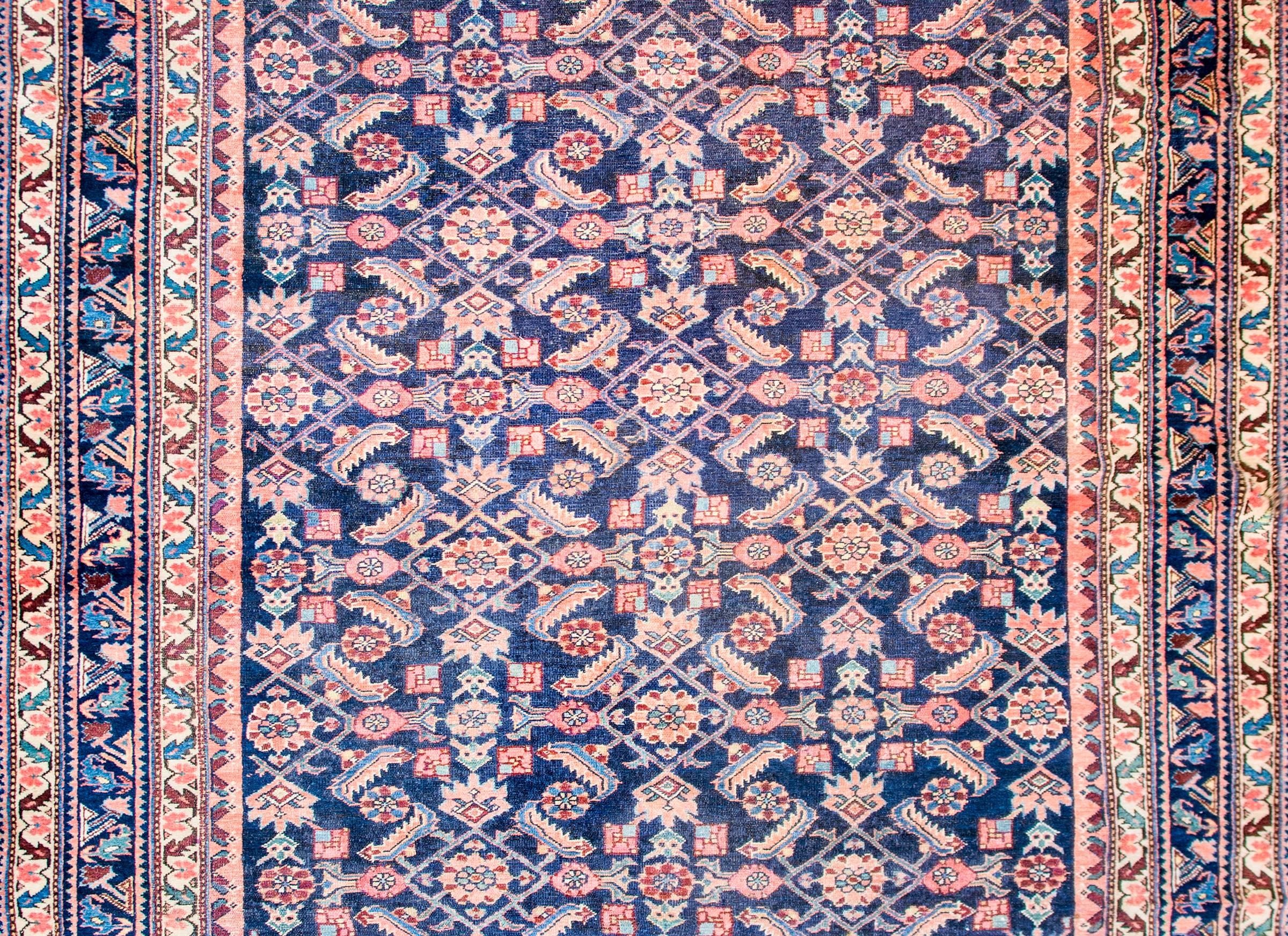 An amazing late 19th century Persian Malayer rug with an all-over trellised floral, leaf, and vine pattern woven in light and dark indigo, crimson, pink, and cream colored wool, on a dark indigo background. The border is composed with one central