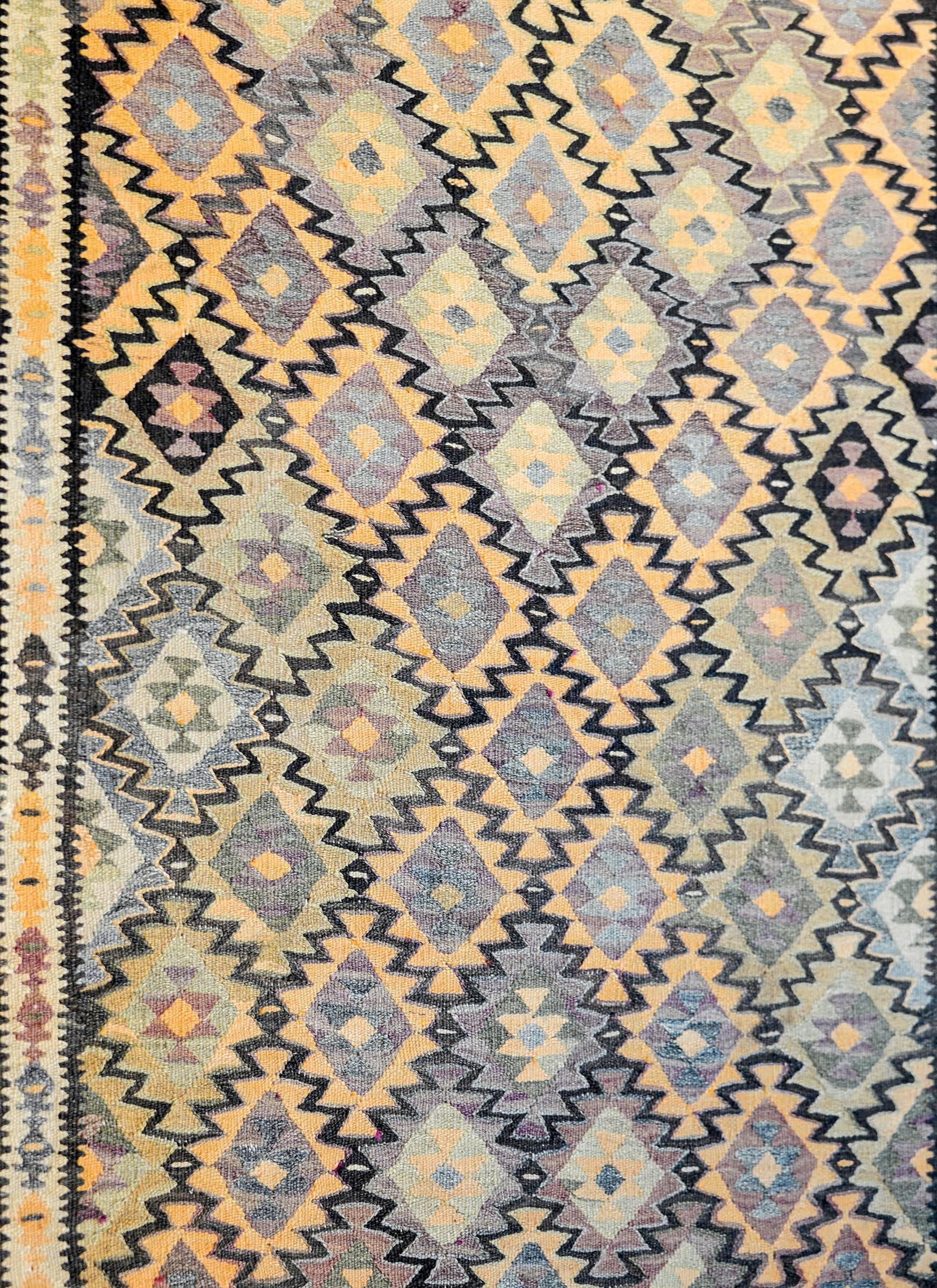 An amazing mid-20th century Persian Qazvin Kilim runner with an multicolored diamond pattern woven in such a way that a larger diamond pattern of orange, lilac, black and natural wool colored diamonds is created. The border is complex, with two