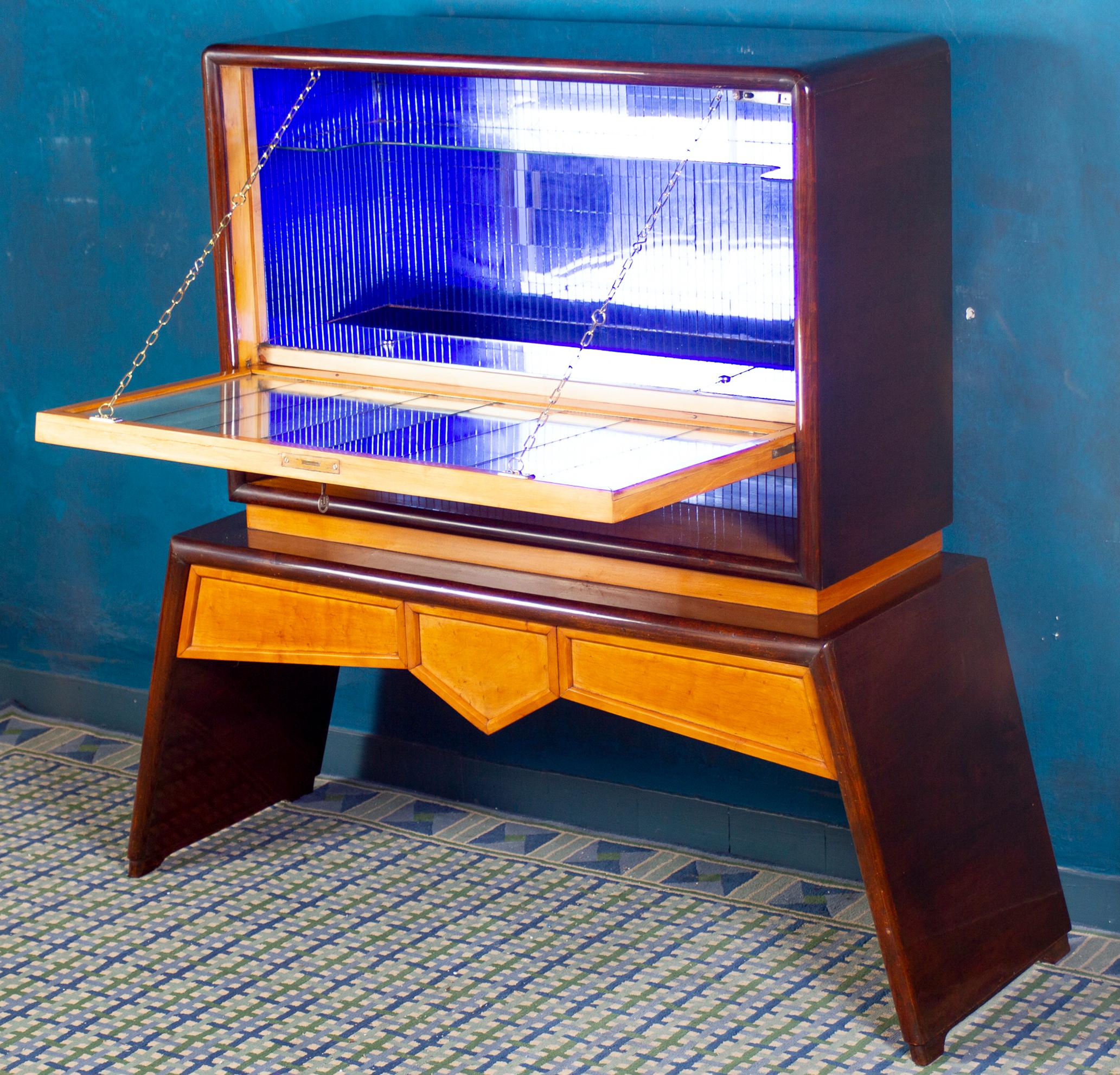 Elegant and unusual bar cabinet.
Decorated front door with geometrical inlaid. Door panels inside with mosaic mirror and brass and glass shelfs. Support with two pull-out drawers.
Finished in two-tone blond birch and dark coffee colors.

