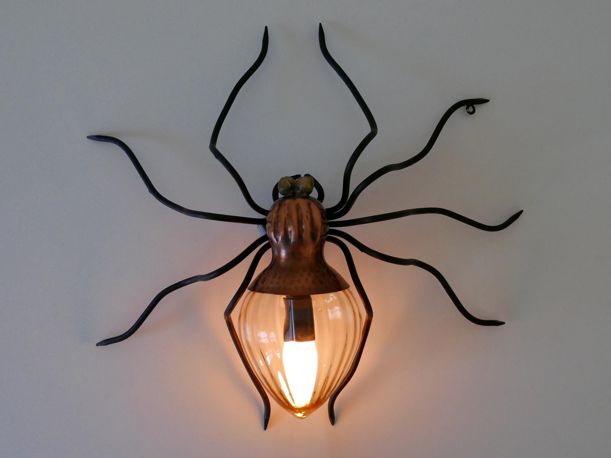 Exceptional, lovely and highly decorative Mid-Century Modern Spider wall lamp or sconce. Designed and manufactured by Rossini Illuminazione, Italy, 1960s.

Executed in hammered copper, black enameled metal, brass and glass, the sconce needs 1 x E14