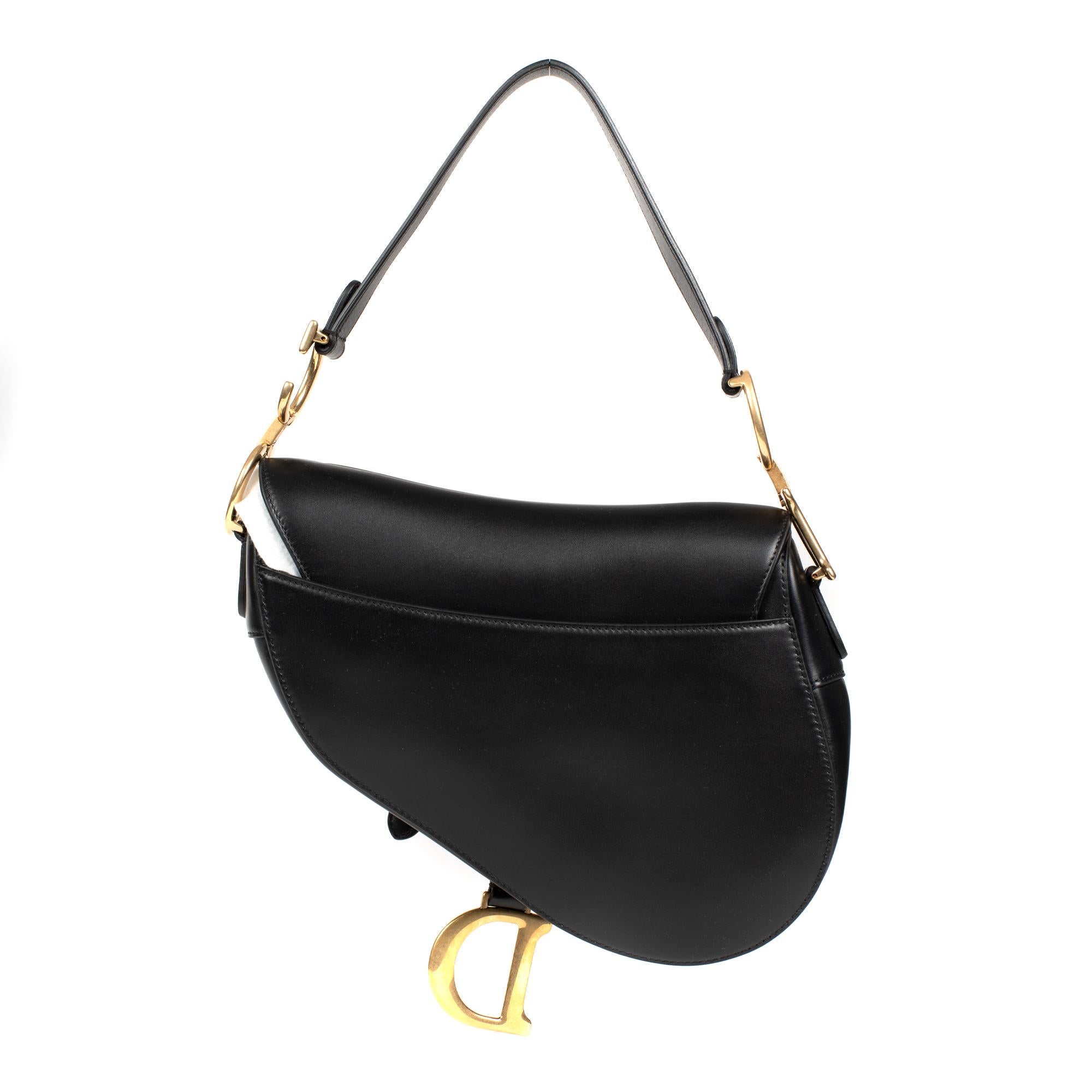 Charming Bag Dior Saddle in black box calf leather box trim in gold-tone metal, simple leather handle allowing a hand or shoulder stand.

Zip closure.
Black leather inner lining.
Signature: 