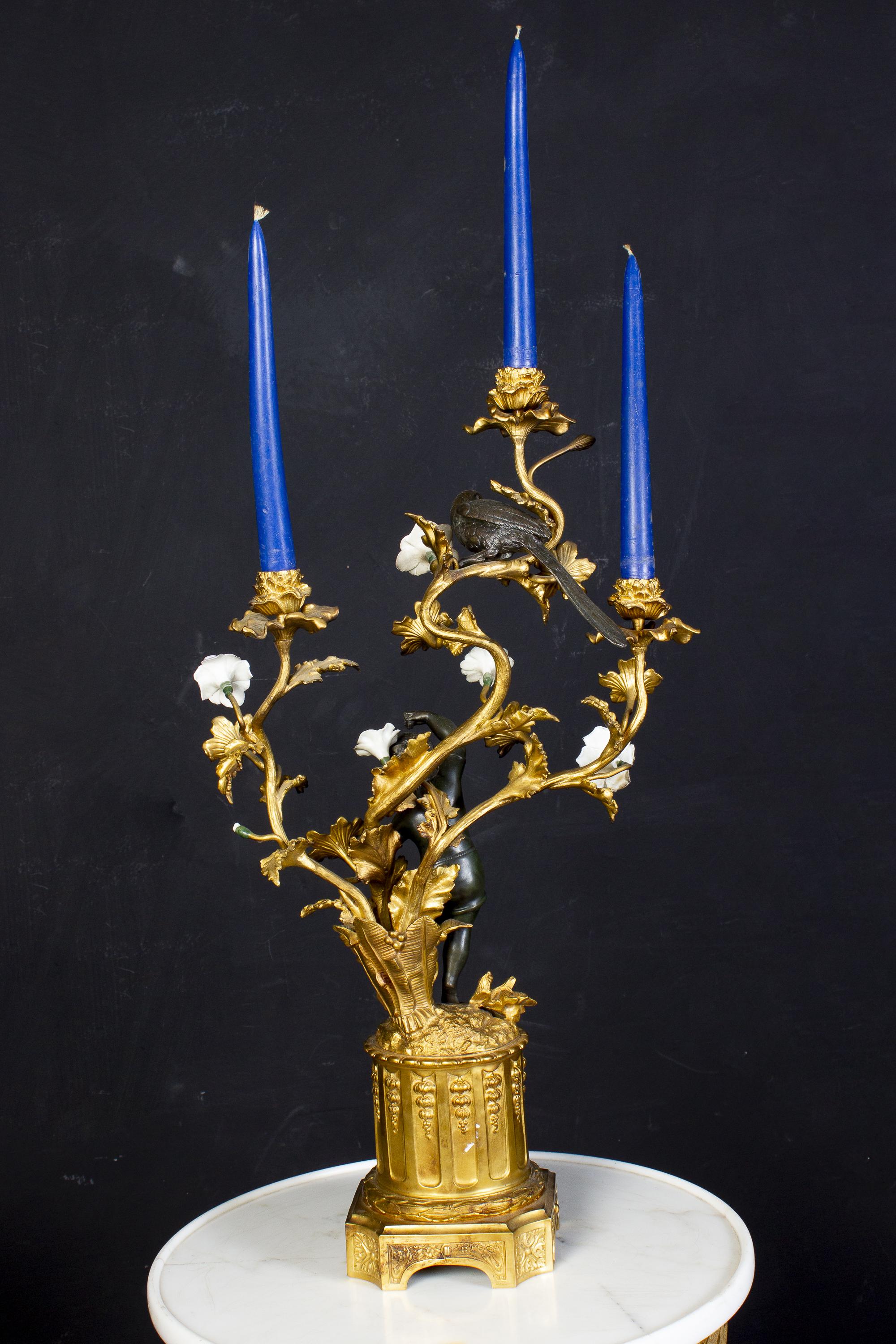 Paire de candélabres français du XIXe siècle en bronze et bronze doré, chacun avec un délicieux bronze foncé dansant des figures de putto et des perroquets tenant en l'air trois branches de bougies à volutes avec des fleurs colorées en porcelaine de