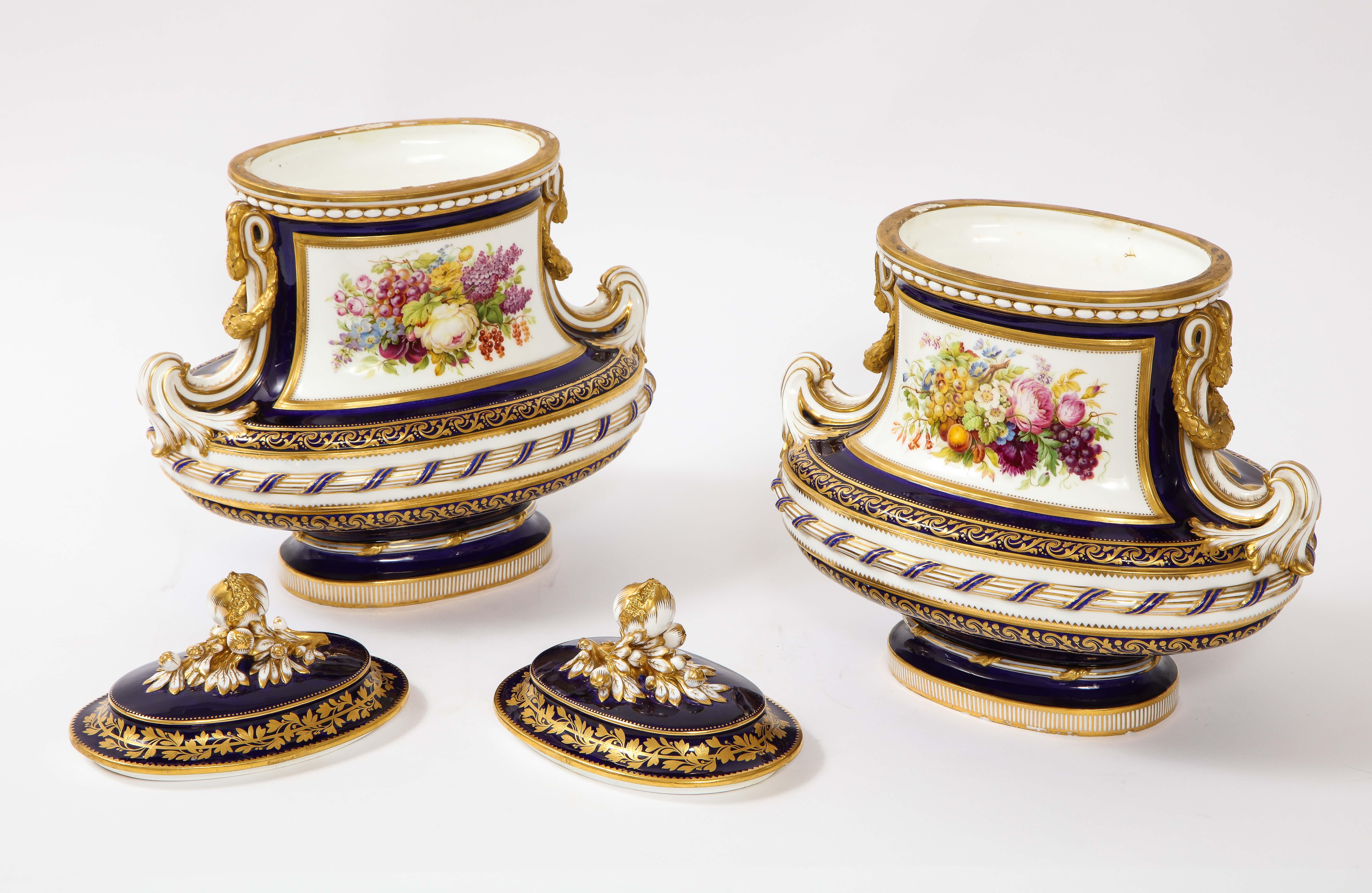 Pareja de jarrones de porcelana Mintons del siglo XIX con fondo azul cobalto y cartuchos con escenas de bodegones. Cada jarrón es de forma oval comprimida con tapas abovedadas desmontables y bases circulares con pedestal. Los paneles centrales de