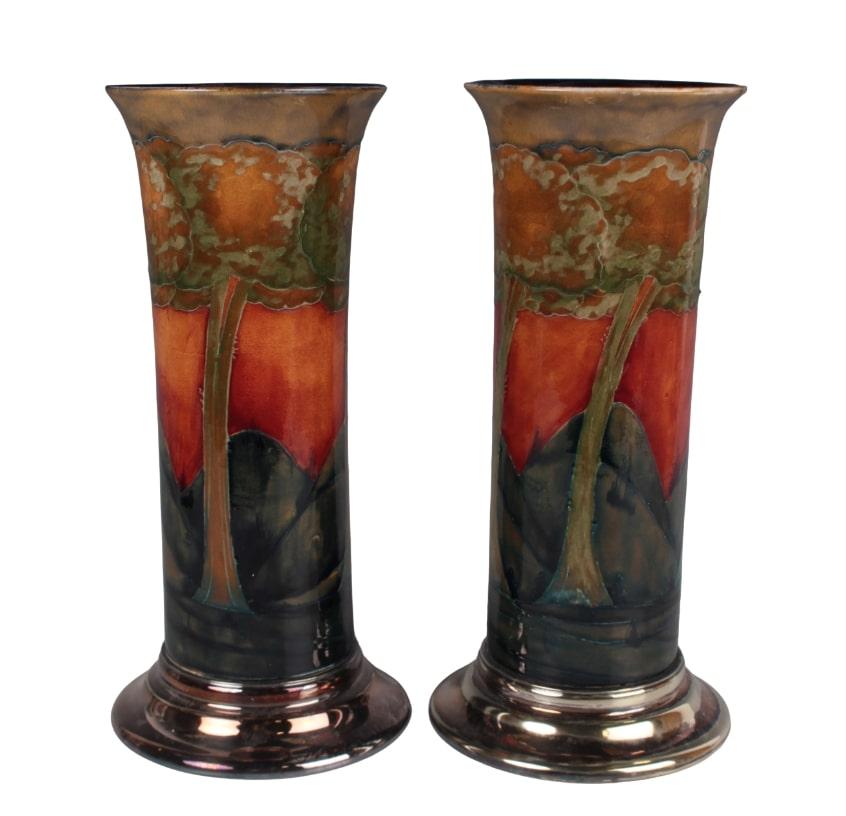 A pair of plate mounted Eventide pattern Moorcroft Pottery vases, circa1925, of cylindrical shape with gently flared rims, the circular plated bases by William Hutton & Sons, impressed factory marks and numerals282, blue painted initials, height