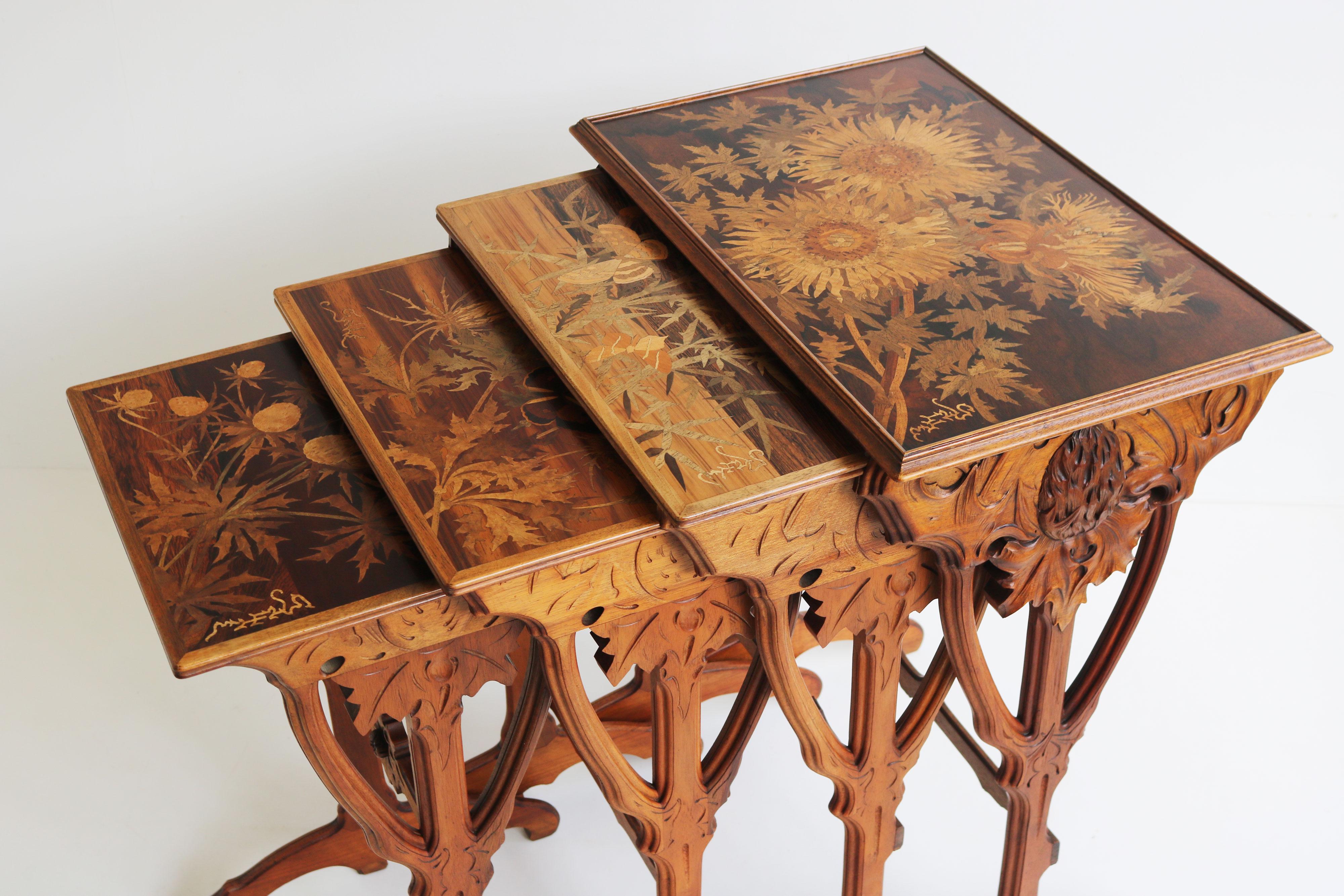 A set of four French Art Nouveau nesting tables by Emile Gallé decorated with fruitwood marquetry in a motif of carlile thistle and butterflies. Each table represents a different stage of growth, with the smallest table showing the newly budded