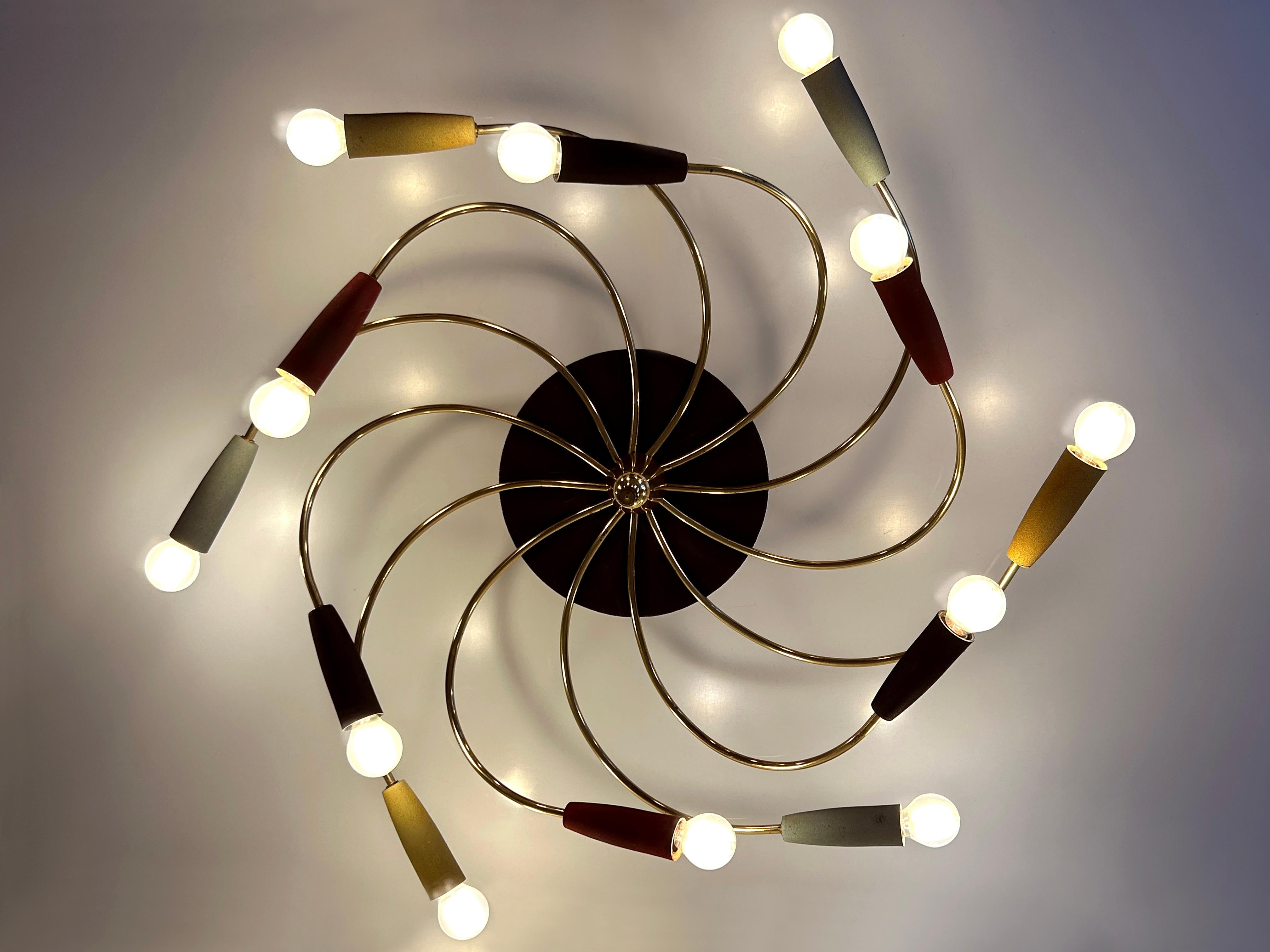 Extremely rare, large, lovely and highly decorative Mid-Century Modern twelve-flamed sputnik ceiling lamp or chandelier 'Tornado'. Designed and manufactured probably in Germany, 1950s.

Executed in brass, plywood and bakelite, the ceiling lamp /