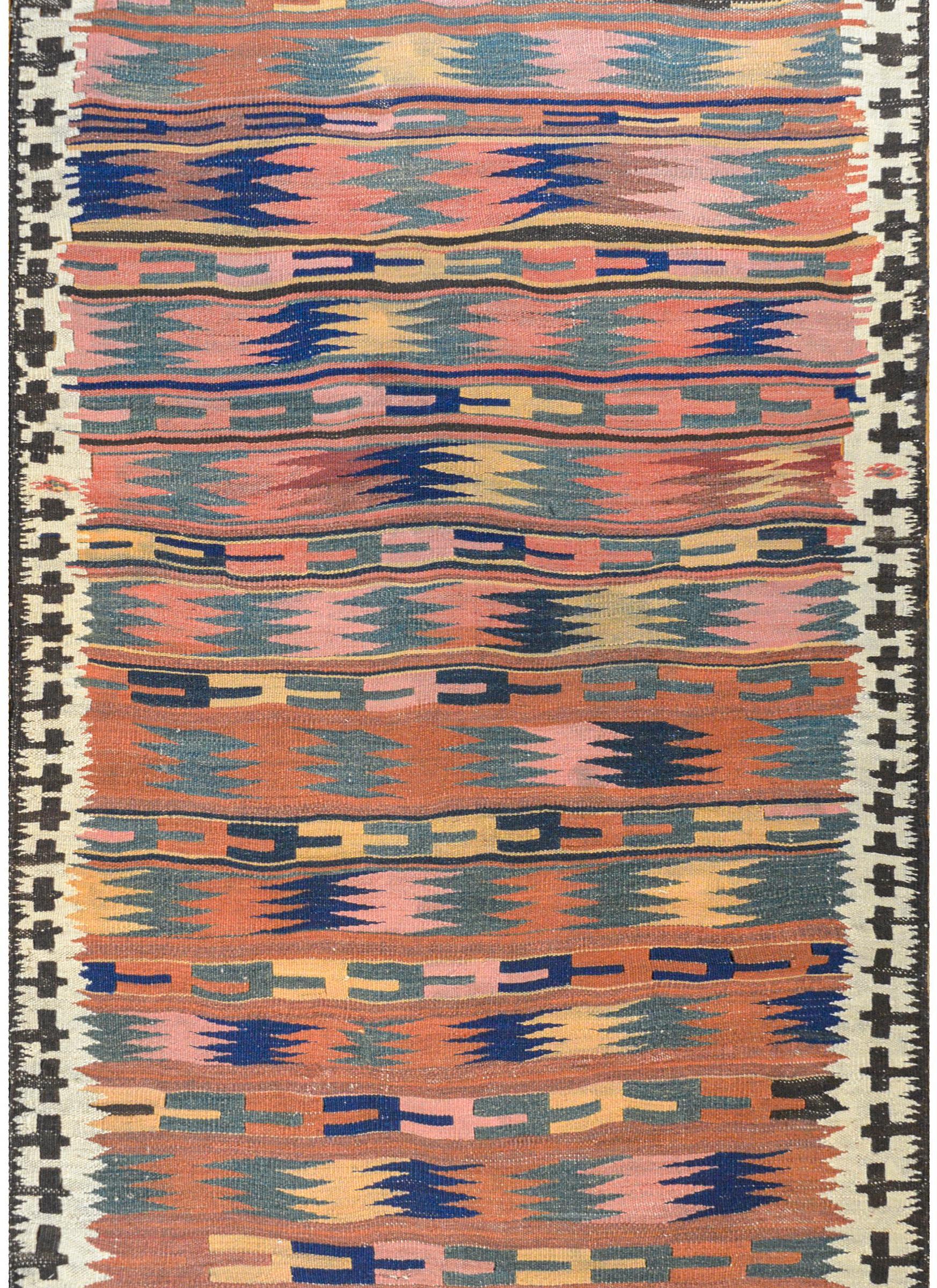 An amazing vintage Bashir Kilimanjaros rug with a striped pattern composed of multiple geometric pattered stripes woven in reds, indigos, greens, golds, browns, and whites, surrounded by a wonderful geometric pattered border.