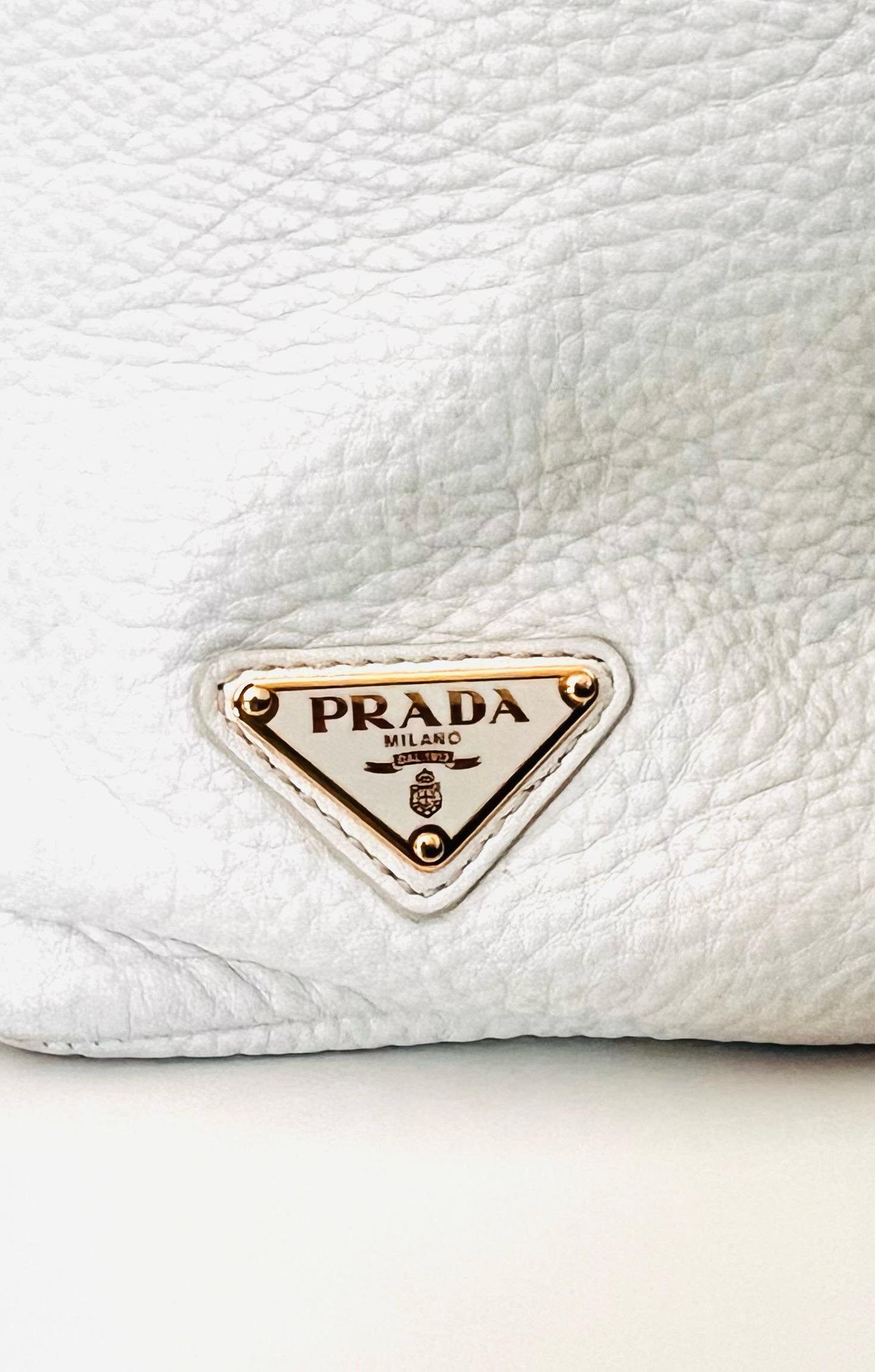 Beautiful and practical PRADA Leather tote bag. 

This shoulder bag features a leather body, gold hardware details, flat leather handles, an open top with magnetic snap button closure, and interior zip pocket. 
White with gold hardware.Wear this as