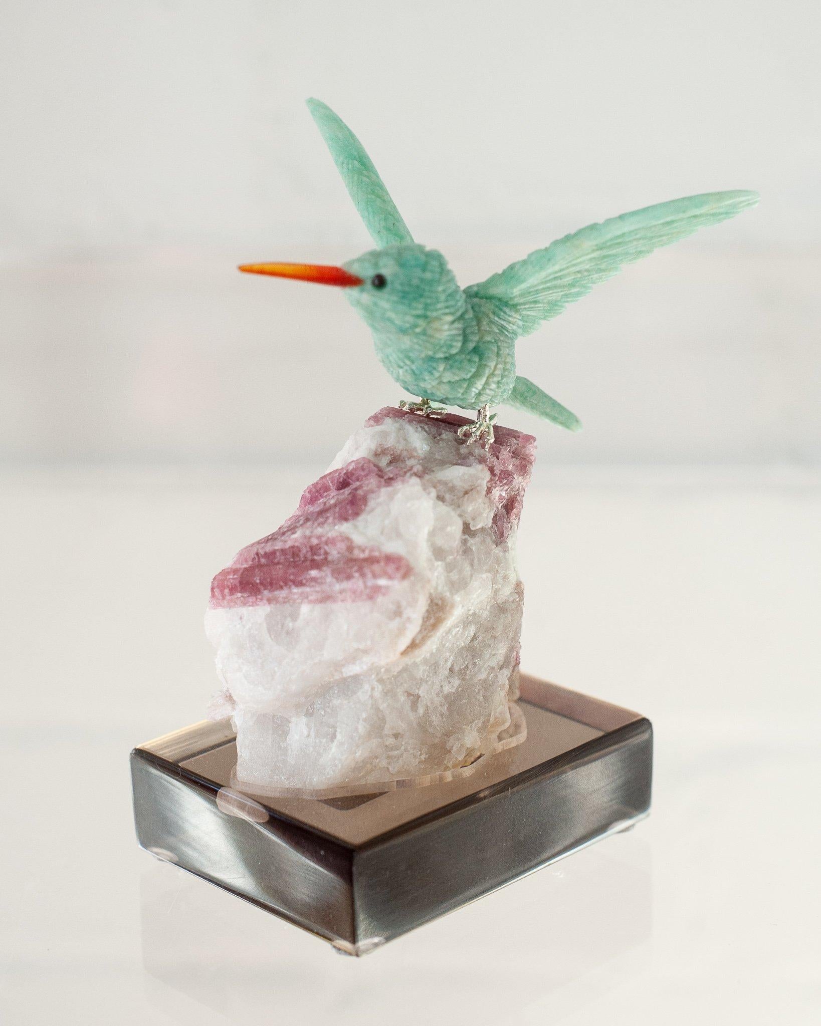A beautiful hand carved semi precious amazonite hummingbird mounted on an rubellite tourmaline mineral specimen base. This exotic bird is a decorative combination of ornithology and geology.