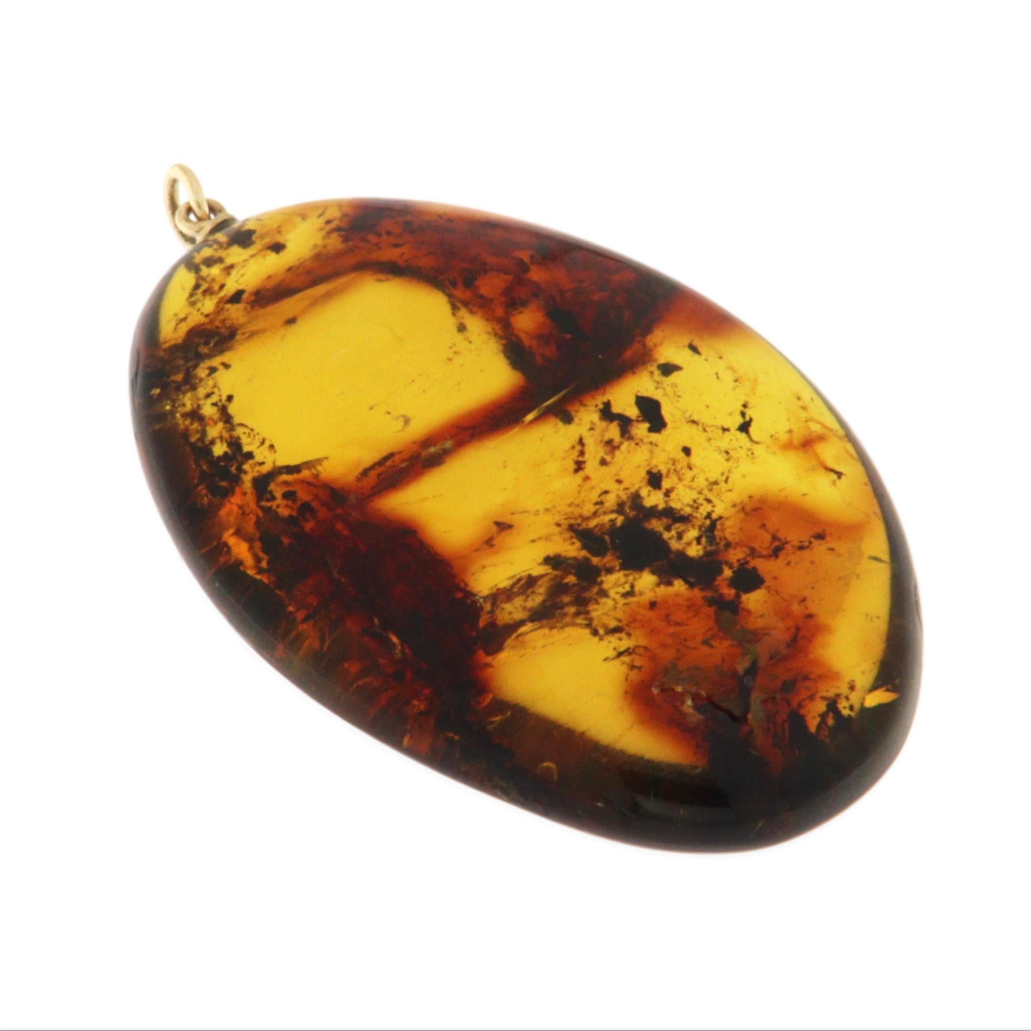 Il protagonista di questo affascinante ciondolo è uno splendido pezzo di ambra naturale, incastonato in un'elegante cornice in oro giallo 14K. L'ambra, con le sue tonalità calde e profonde, è modellata in un grande ovale liscio che è stato