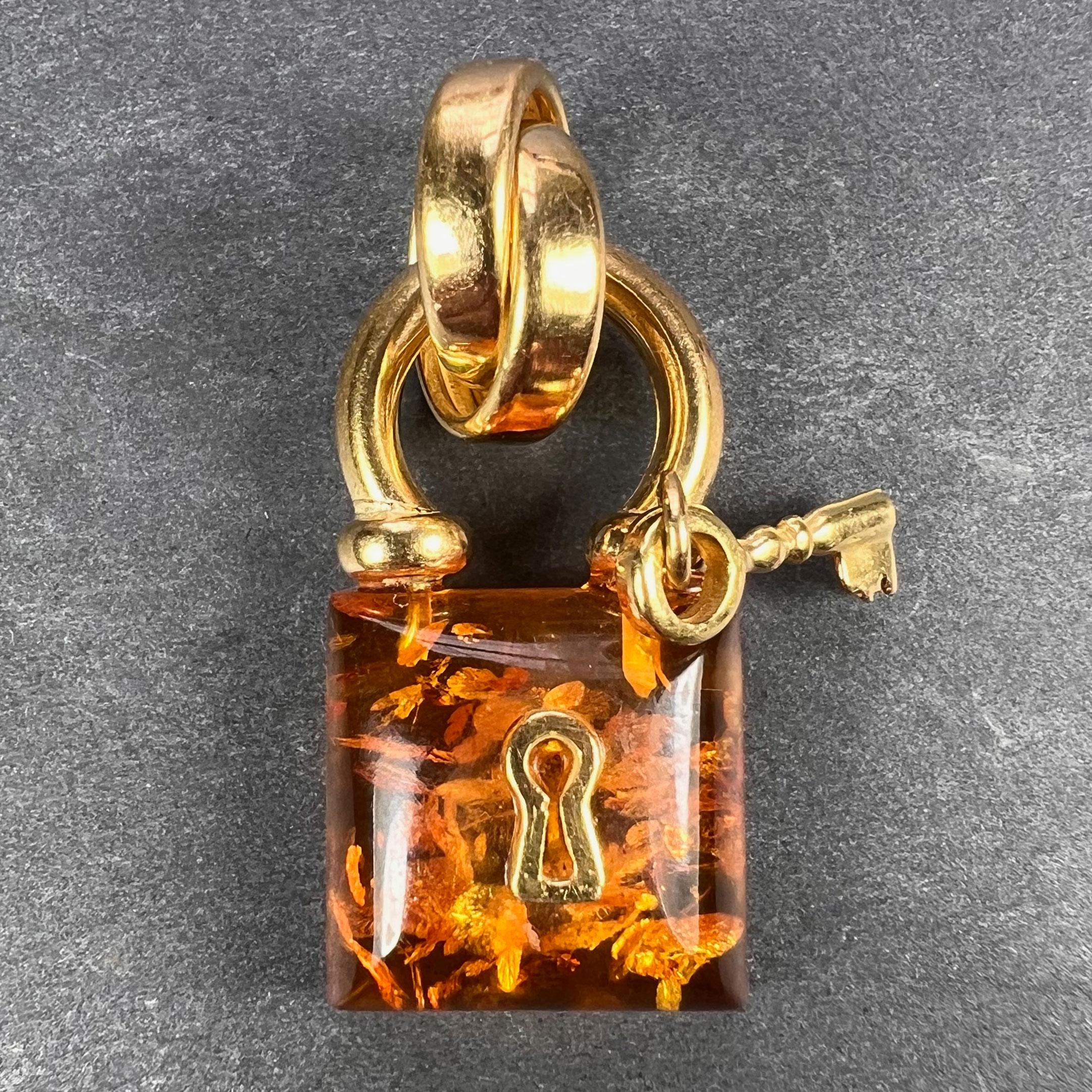 An 18 karat (18K) yellow gold and clarified amber charm pendant designed as a padlock with key. Stamped with the owl mark for French import and 18 karat gold.

Dimensions: 3.3 x 1.4 x 0.75 cm (not including jump ring)
Weight: 3.83 grams