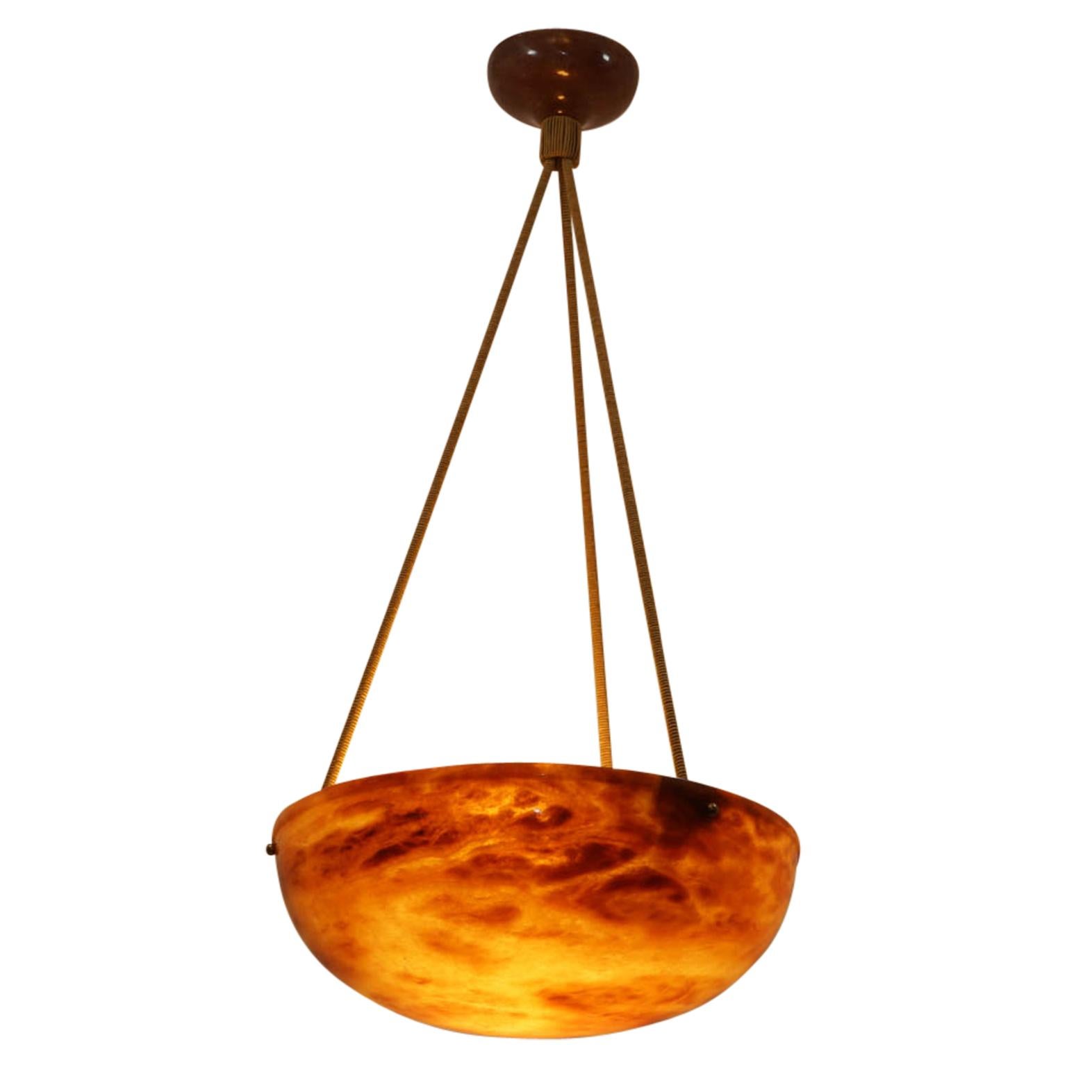 Carved from a choice piece of light amber alabaster with a simple single upper rim, the fixture is suspended on a set of three electrified silk ropes, holding three 40 watt incandescent bulbs, or higher wattage LED bulbs.