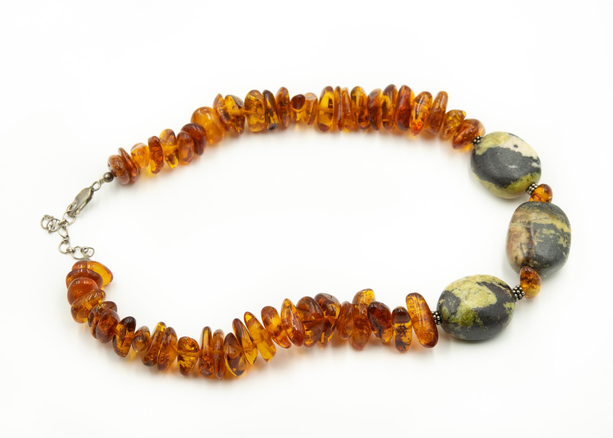 Vintage large freeform baltic honey amber bead necklace featuring sterling silver beaded rondelles as well as an adjustable sterling silver lobster clasp.  The amber is accented by 3 large black and green stones.  The necklace can be adjusted from