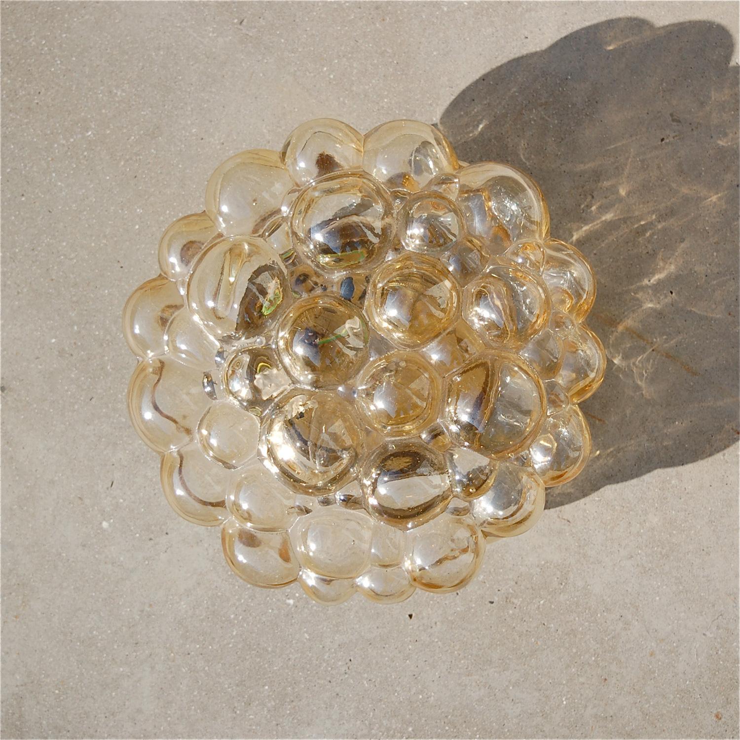 A bubble glass lamp designed by Helena Tynell for Glashütte Limburg (Germany) in a warm yellow, light gold or amber colour. It can be used both as a wall sconce or a flush mounted ceiling light. It has a very playful and organic shape, mimicking air