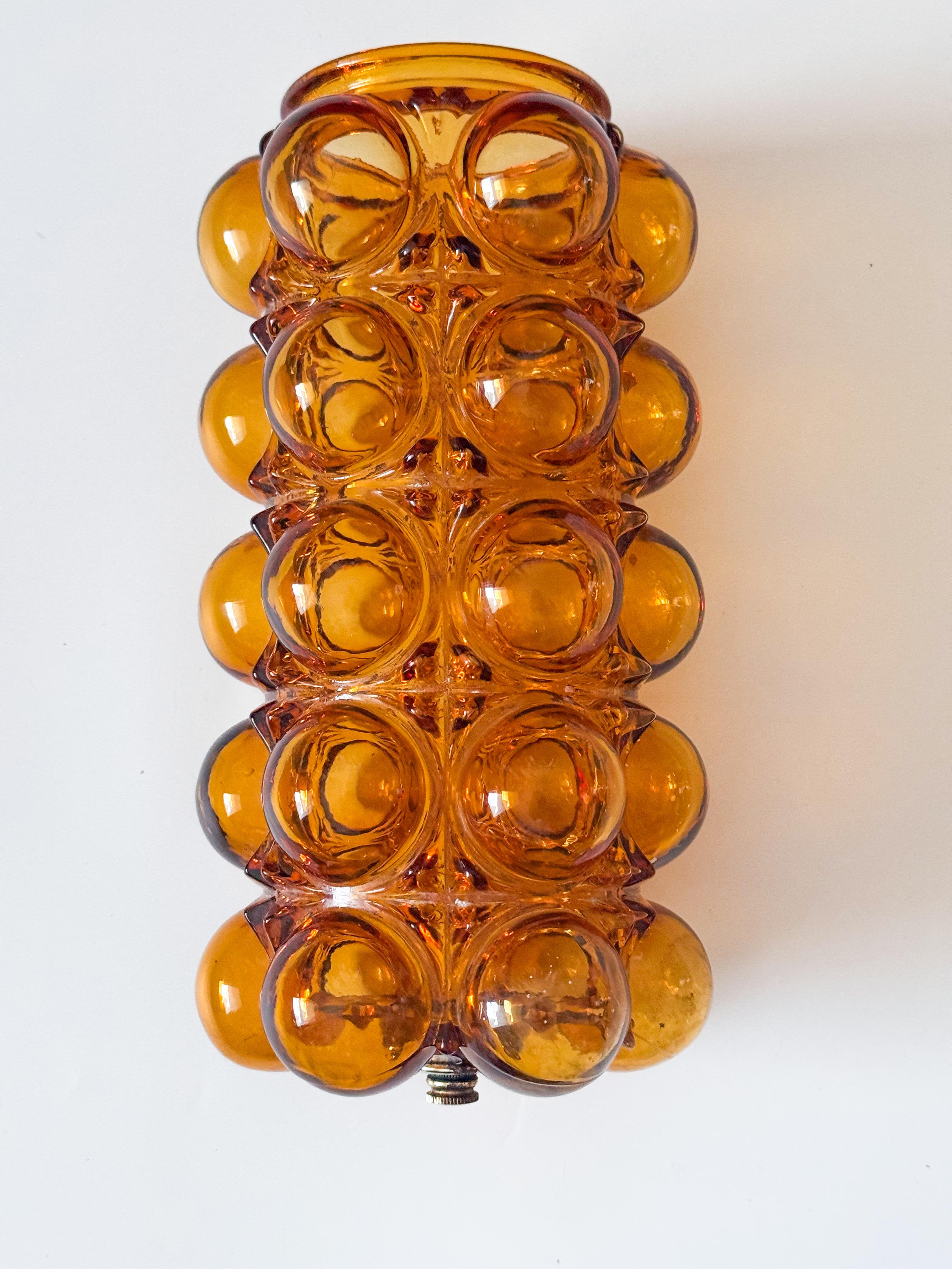 This sculptural amber bubble glass flush mount ceiling lamp is a striking mid-century piece in the style of Helena Tynell, , echoing the bold and playful designs of 1960s-70s German lighting.  Featuring a richly detailed amber bubble glass dome on a