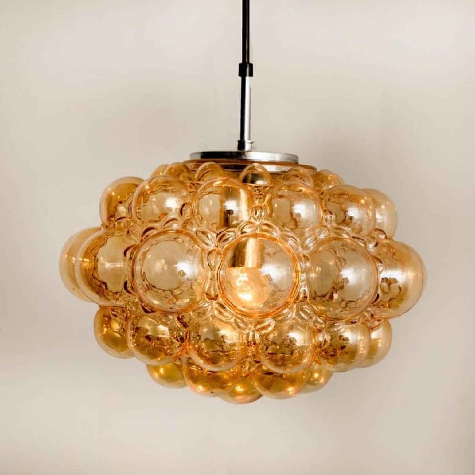 Un bellissimo lampadario o pendente in vetro a bolle d'aria disegnato da Helena Tynell per Glashütte Limburg. Un classico del design, il vetro soffiato a mano dona una meravigliosa luce calda.

Le dimensioni: Altezza 80 cm dal soffitto, diametro 30