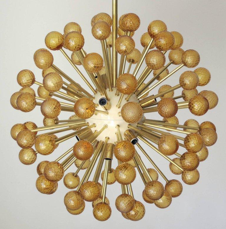 Lustre Sputnik moderne italien avec des sphères en verre de Murano ambre texturé soufflé à la main, montées sur des cadres en laiton avec des centres émaillés crème / Design by Fabio Bergomi for Fabio Ltd / Made in Italy 
16 lampes / type E12 ou E14