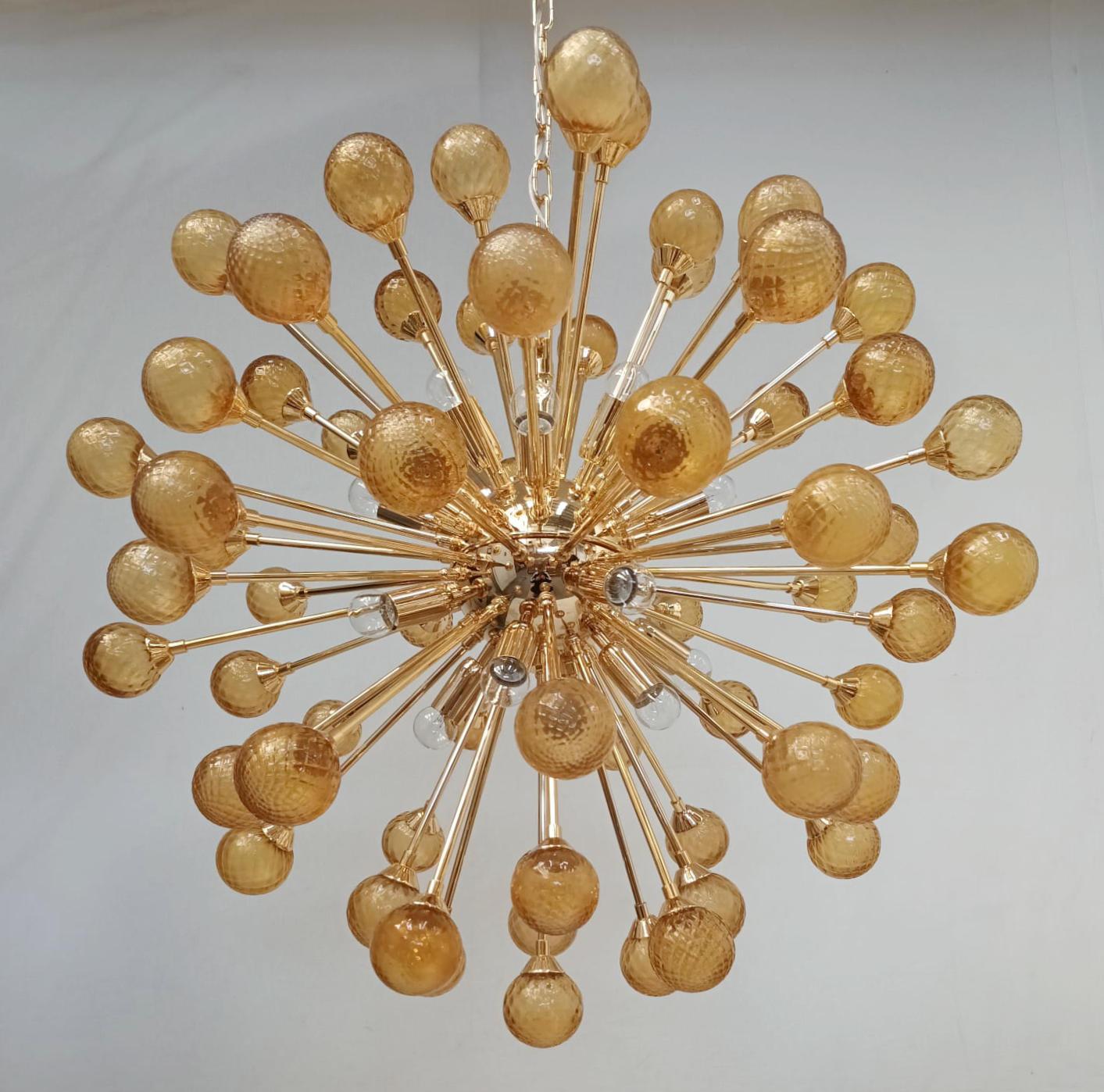 Moderna araña sputnik italiana con esferas de cristal de Murano sopladas a mano con textura de ámbar, montadas sobre una estructura metálica con acabado dorado / Made in Italy
16 luces / tipo E12 o E14 / máx. 40W 
Medidas: diámetro 31,5 pulgadas,