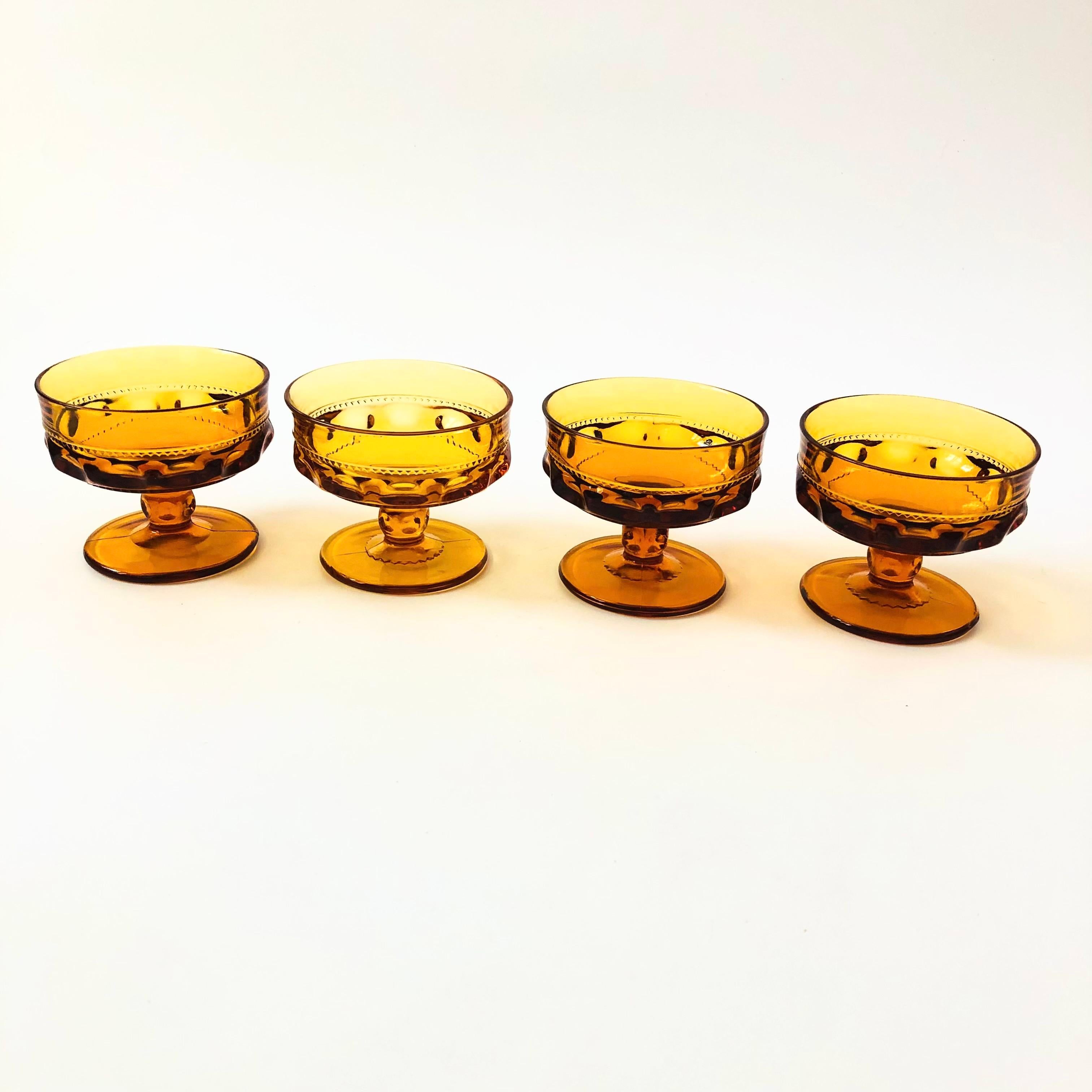 A set of 4 gorgeous coupe glasses with a lovely ornate design in amber glass. Made in the King's Crown pattern by Indiana Glass. Perfect for champagne, wine, or cocktails.

