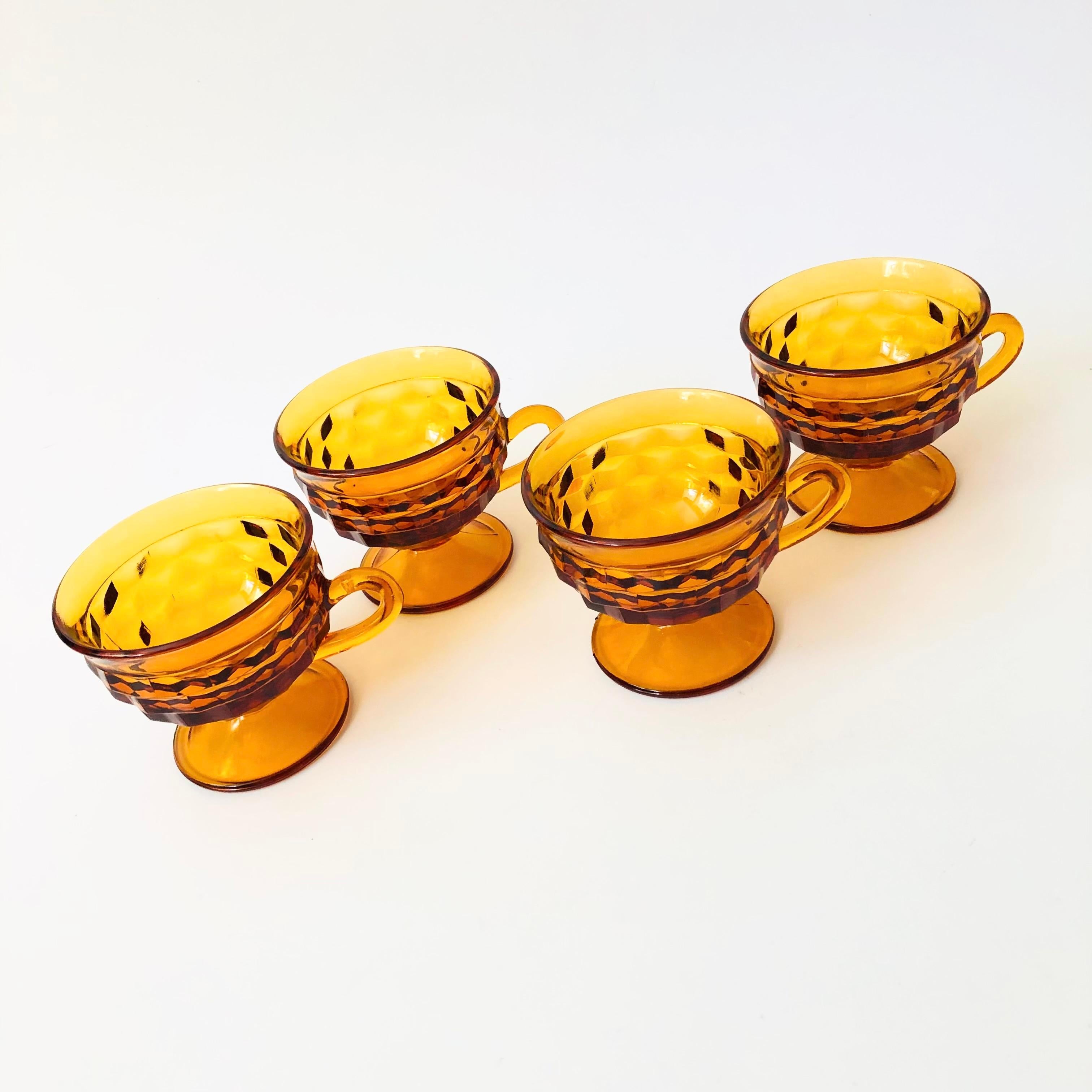 A set of 4 vintage coupe glasses with a cubist design in amber glass. Made in the Whitehall pattern by Indiana Glass. Each has a little handle formed on one side. Perfect for wine or champagne. Smooth interiors.

