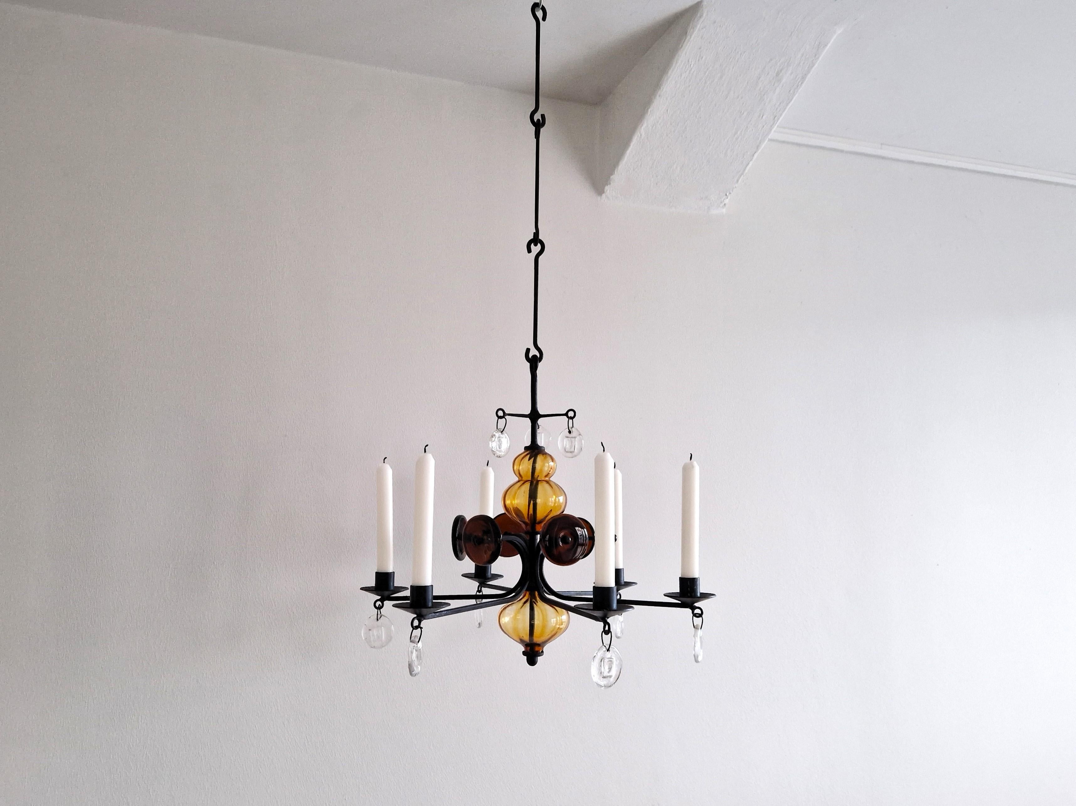 This beautiful amber and clear art glass on wrought iron candelabra chandelier was designed by Erik Höglund for Boda Glasbruk & Smide. Höglund (1932–1998) was one of the brightest stars of 20th-century Swedish glass design. This 6 arm chandelier is