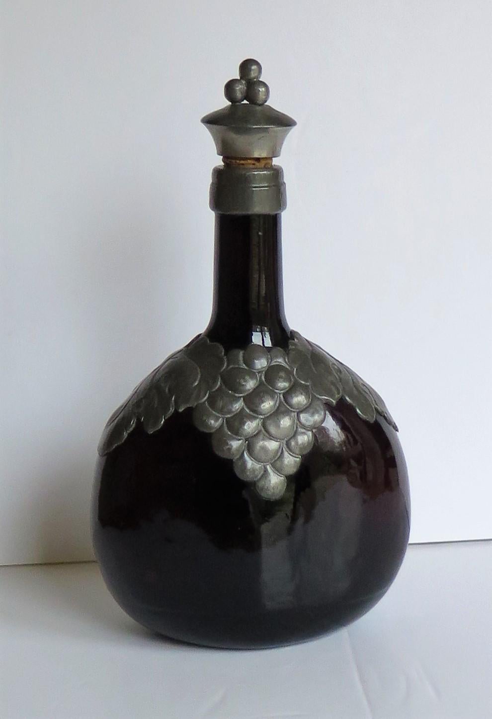 This is a good, dark amber glass bottle or decanter fitted with a pewter grape and leaf collar and a cork and pewter stopper, all in an Art Nouveau style, which we attribute to a Danish maker in the 19th century, circa 1870.

The bottle is flagon