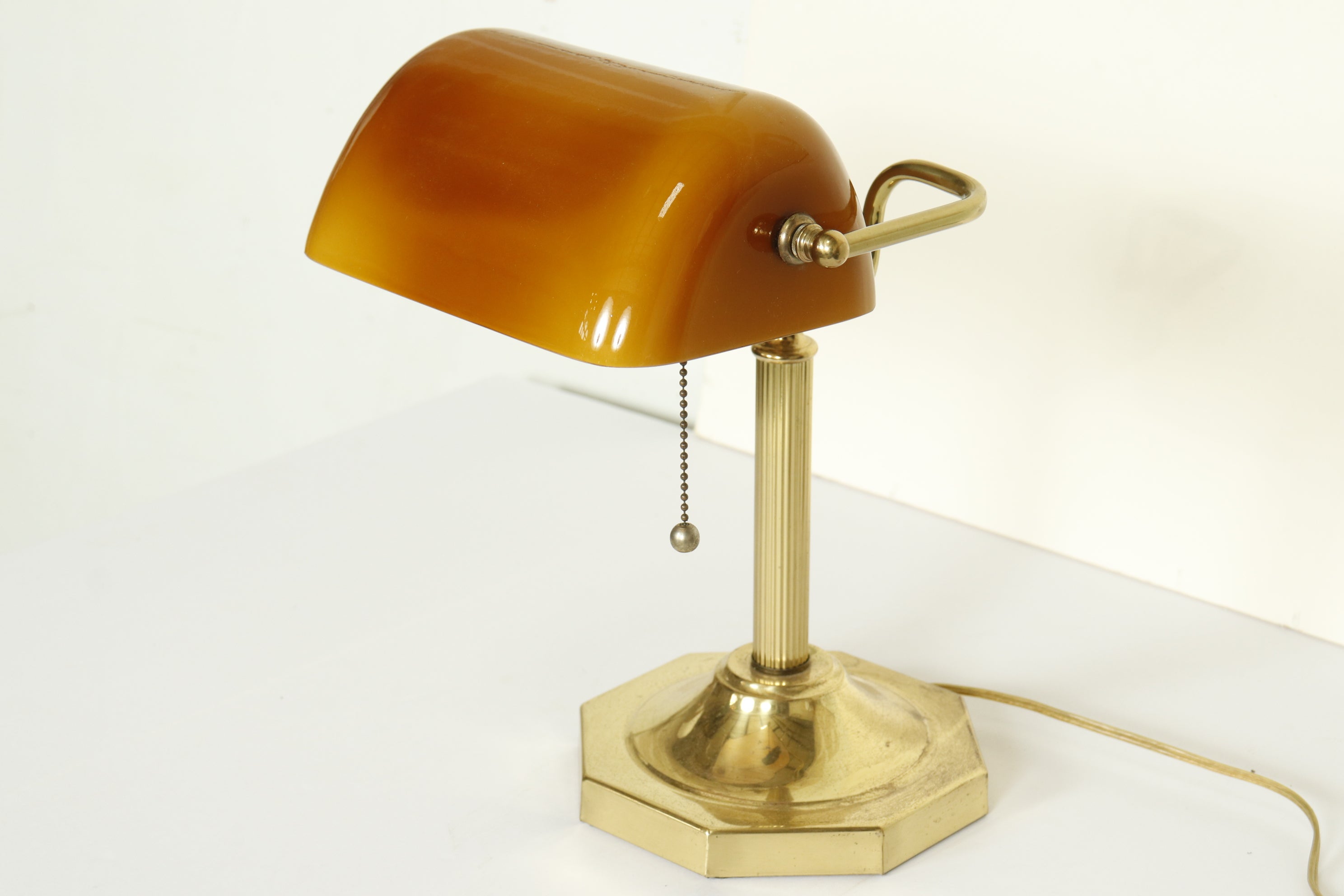 A classic bankers lamp with a unique amber-colored glass shade.

Features:
*Polished brass base
*Adjustable shade
*UL Listed
*Wired for US use
*Takes one standard base bulb

Dimensions: 14.5” H x 7.5” W x 4” D.