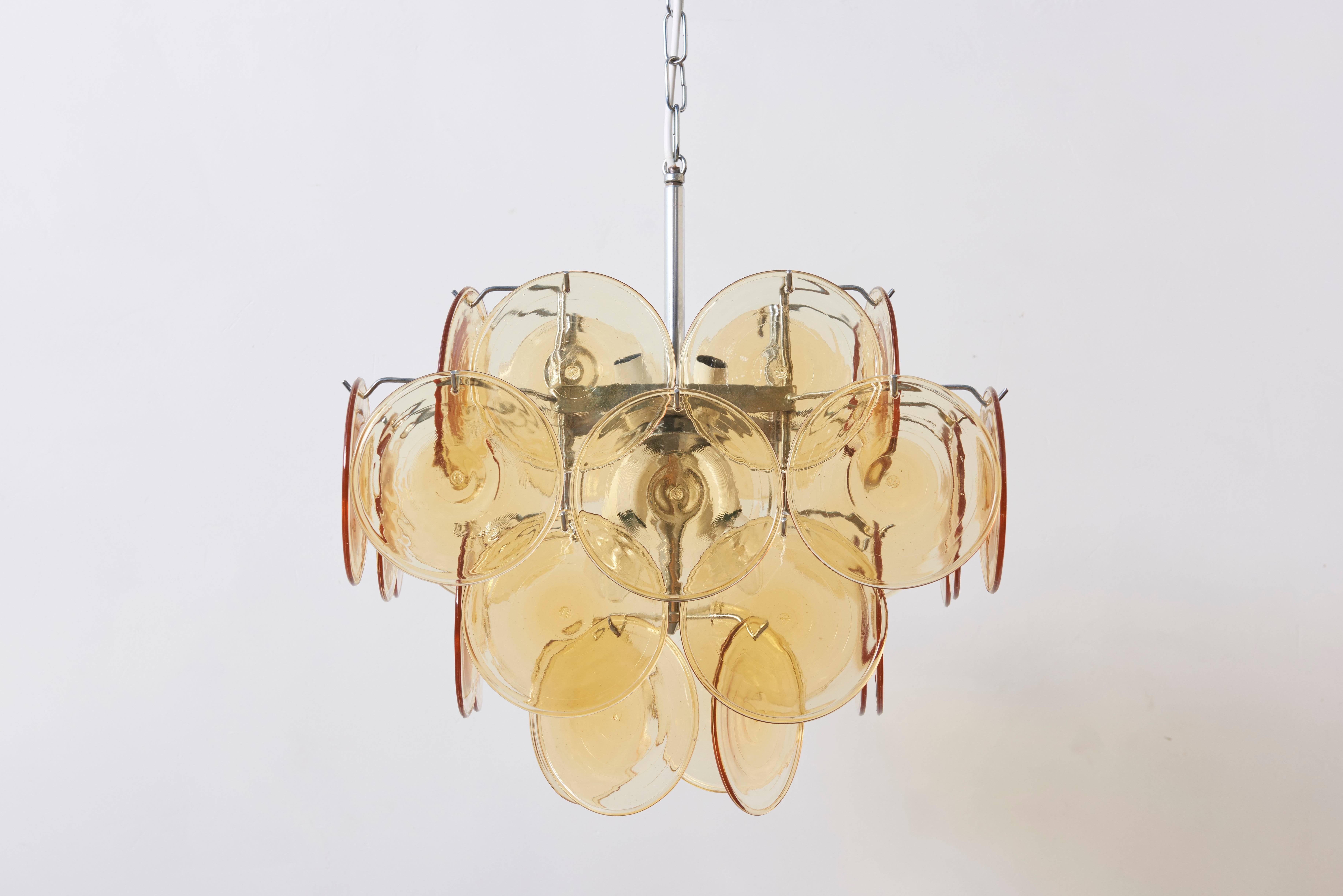 Midcentury colorful Italian chandelier by Vistosi with four tiers of 32 amber colored glass discs and chrome hardware.
The chandelier lights on eight small bulbs. Diameter 45 cm, height with chain 80 cm and height only the glass discs 40 cm.
Free