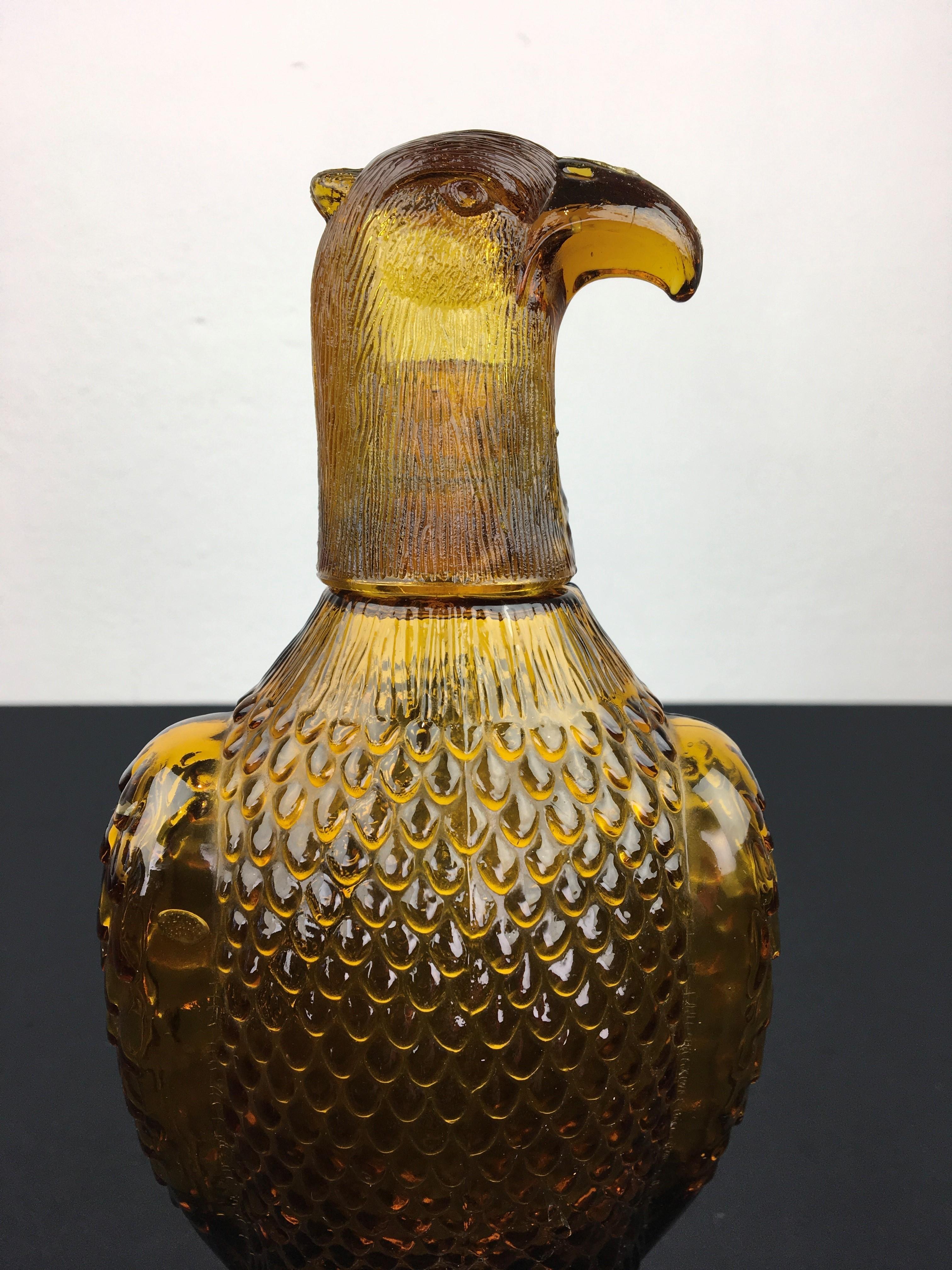 Amber glass decanter bottle in the shape of an Eagle bird. 
This glass eagle decanter is detailed and in the style of the Empoli glass decanter bottles. It will look great at your home bar or between your collection of decanter bottles. The head of