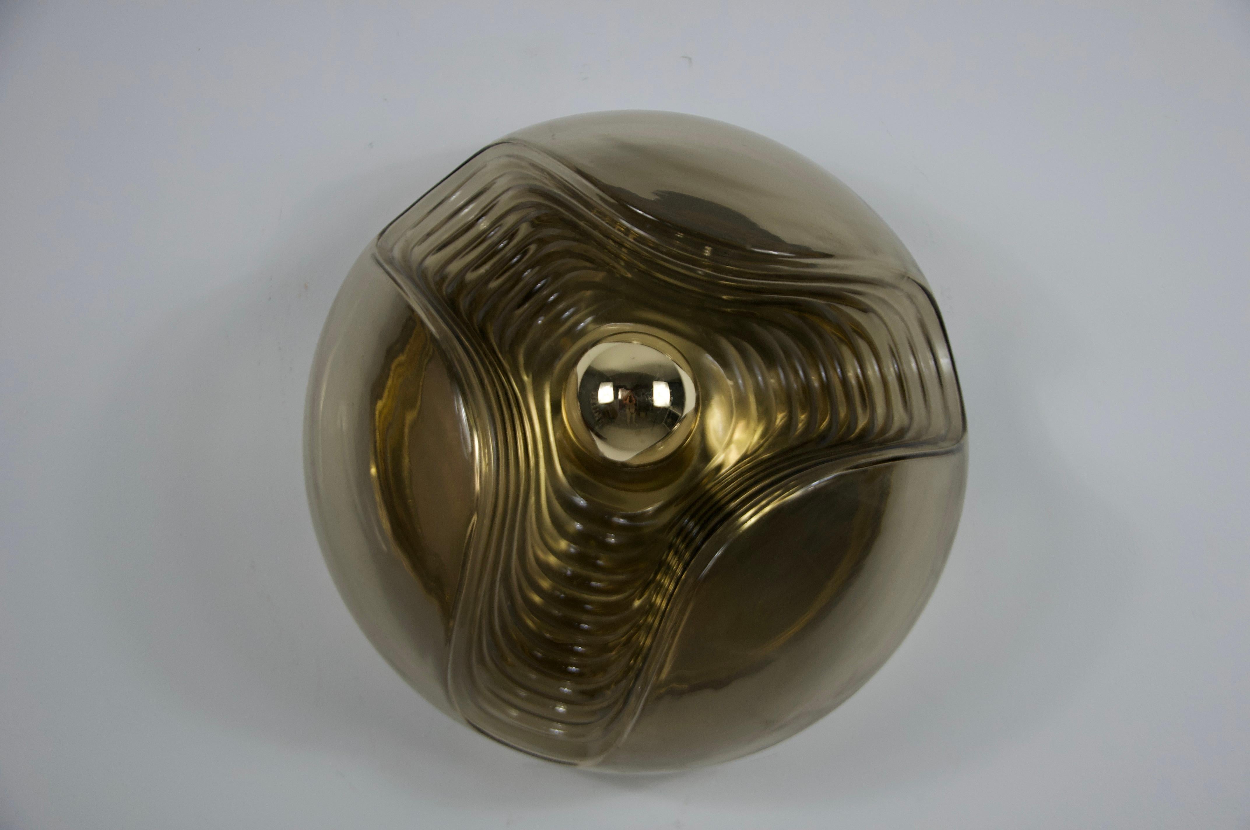 Este empotrable redondo de Koch & Lowy para Peill & Putzler, fabricado en Alemania en la década de 1960, cautiva con su hermoso cristal. La lámpara encarna el distintivo diseño de la Era Espacial de la época, caracterizado por formas futuristas y