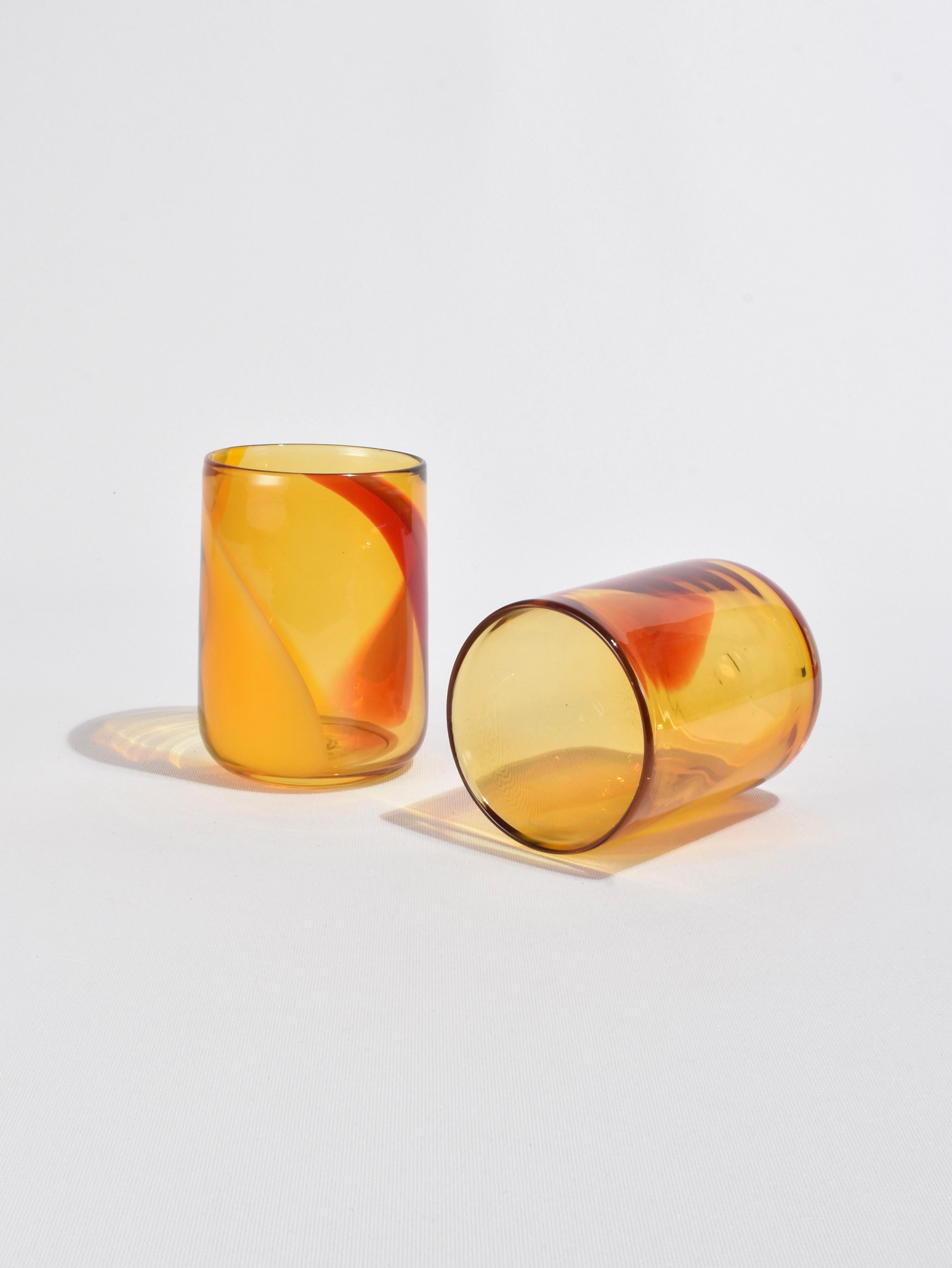 Beautiful blown glass tumblers in amber with orange and red swirls.