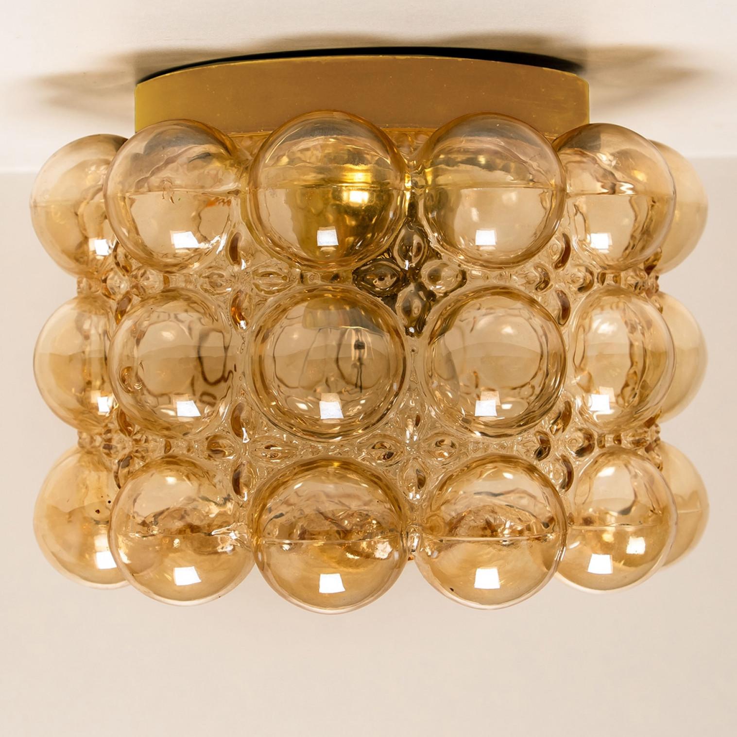 1 des 4 magnifiques appliques ou montures encastrées en verre bullé conçues par Helena Tynell pour Glashütte Limburg. Un classique du design, le verre soufflé à la main de couleur ambre ou tonique donne une lueur merveilleuse et chaleureuse.