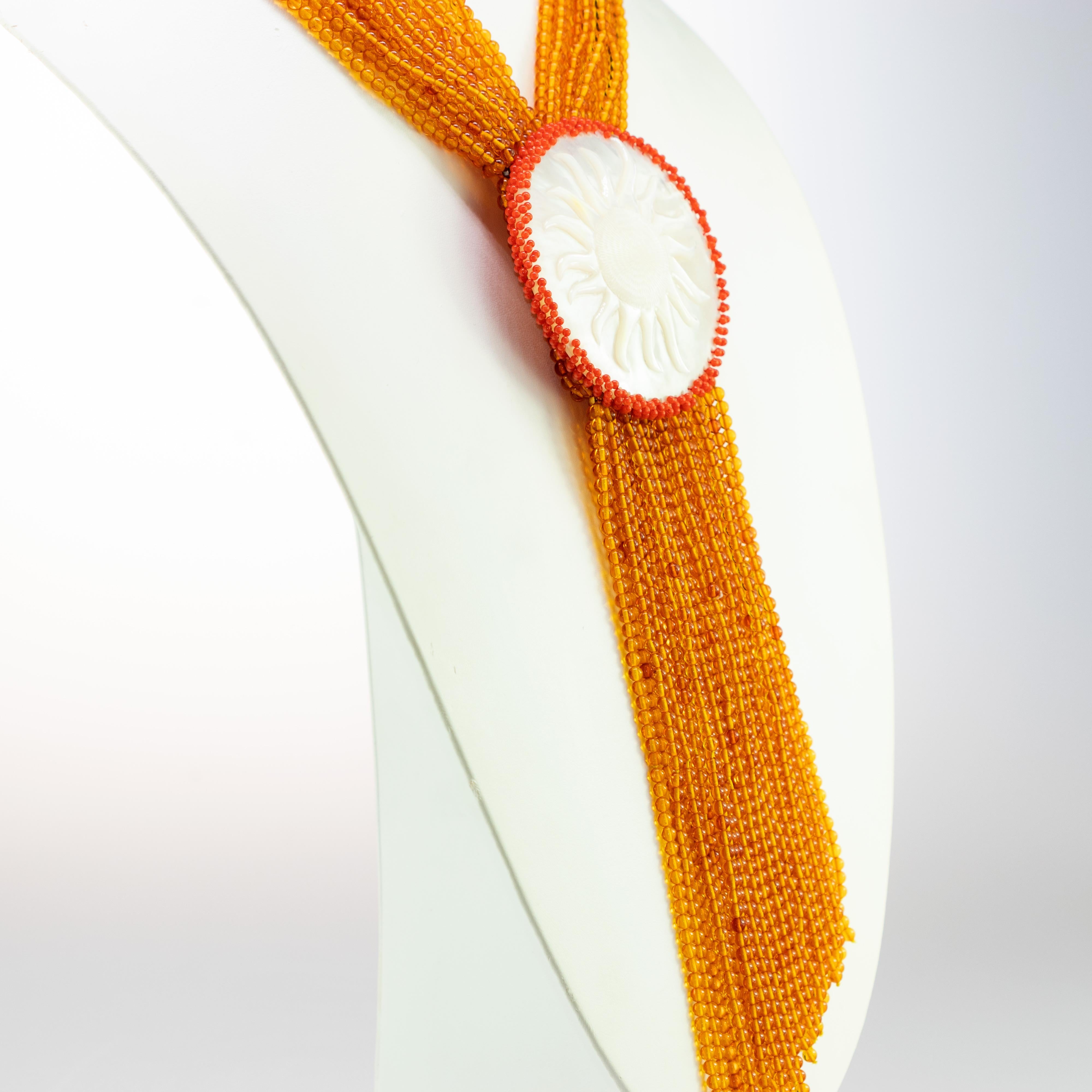 Design luminoso in ambra e ciondolo con sole in madreperla circondato da corallo rosso.

Questa collana unica è ispirata ad Alectrona, la dea greca del sole. Era la causa per cui gli uomini si svegliavano dal sonno ogni mattina grazie alla sua