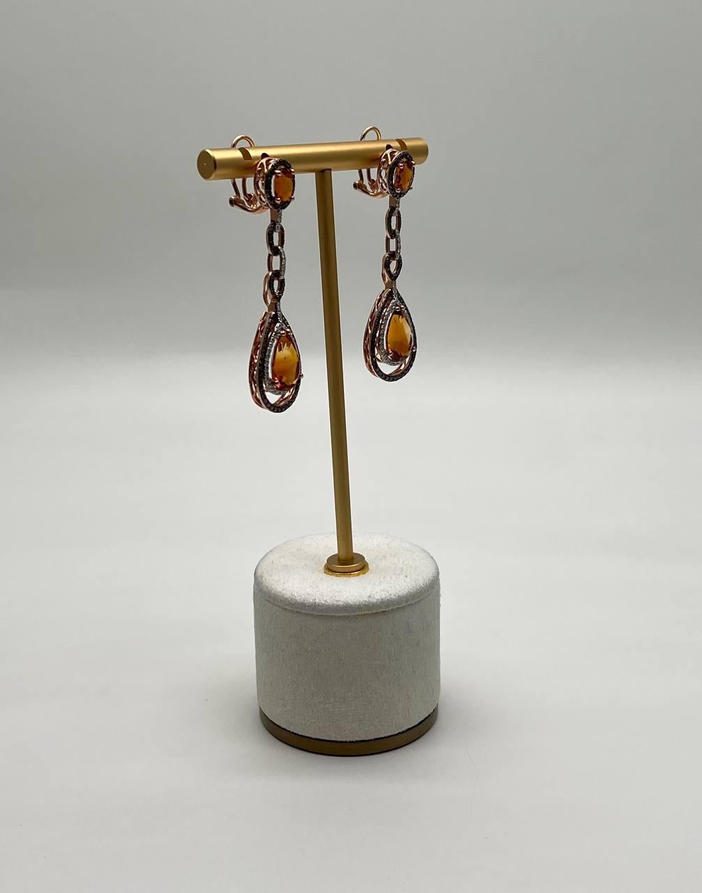 Enhance your elegance with these stunning earrings.
Crafted with precision, the earrings feature rich amber orange citrines set in a teardrop design, suspended from a delicate chain of linked ovals. The warm hues of the stones are beautifully