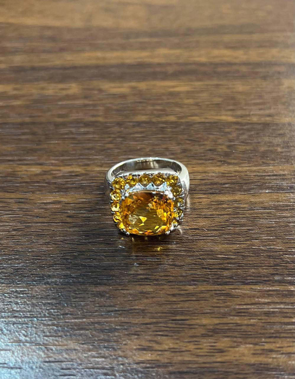 Elegant Multi-Stone Ring with Citrine and Citrines Accents. This striking ring features a large, vibrant citrine as the centerpiece, surrounded by a halo of sparkling citrine accents. The citrine is expertly cut to enhance its brilliance and is