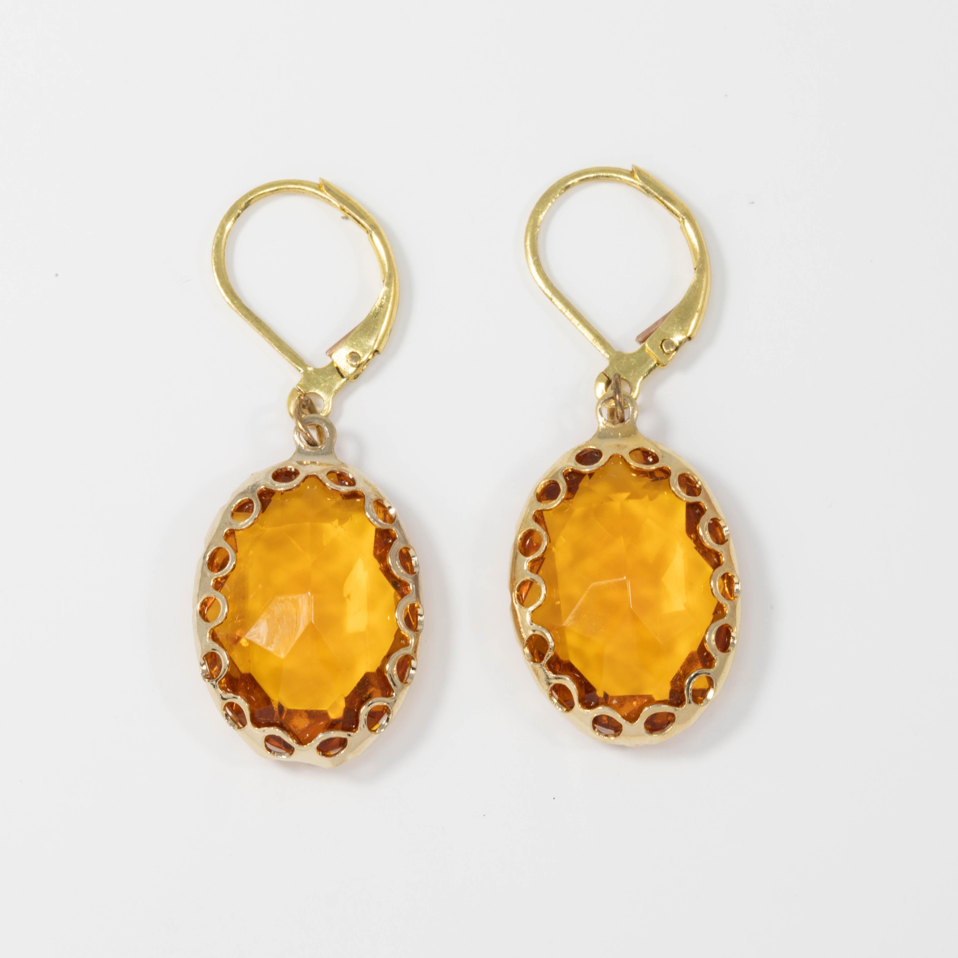 A pair of bright amber-yellow crystal dangling earrings. Each crystal is set in a decorative gold tone bezel. Lever back hook finding.

Circa mid 1900s