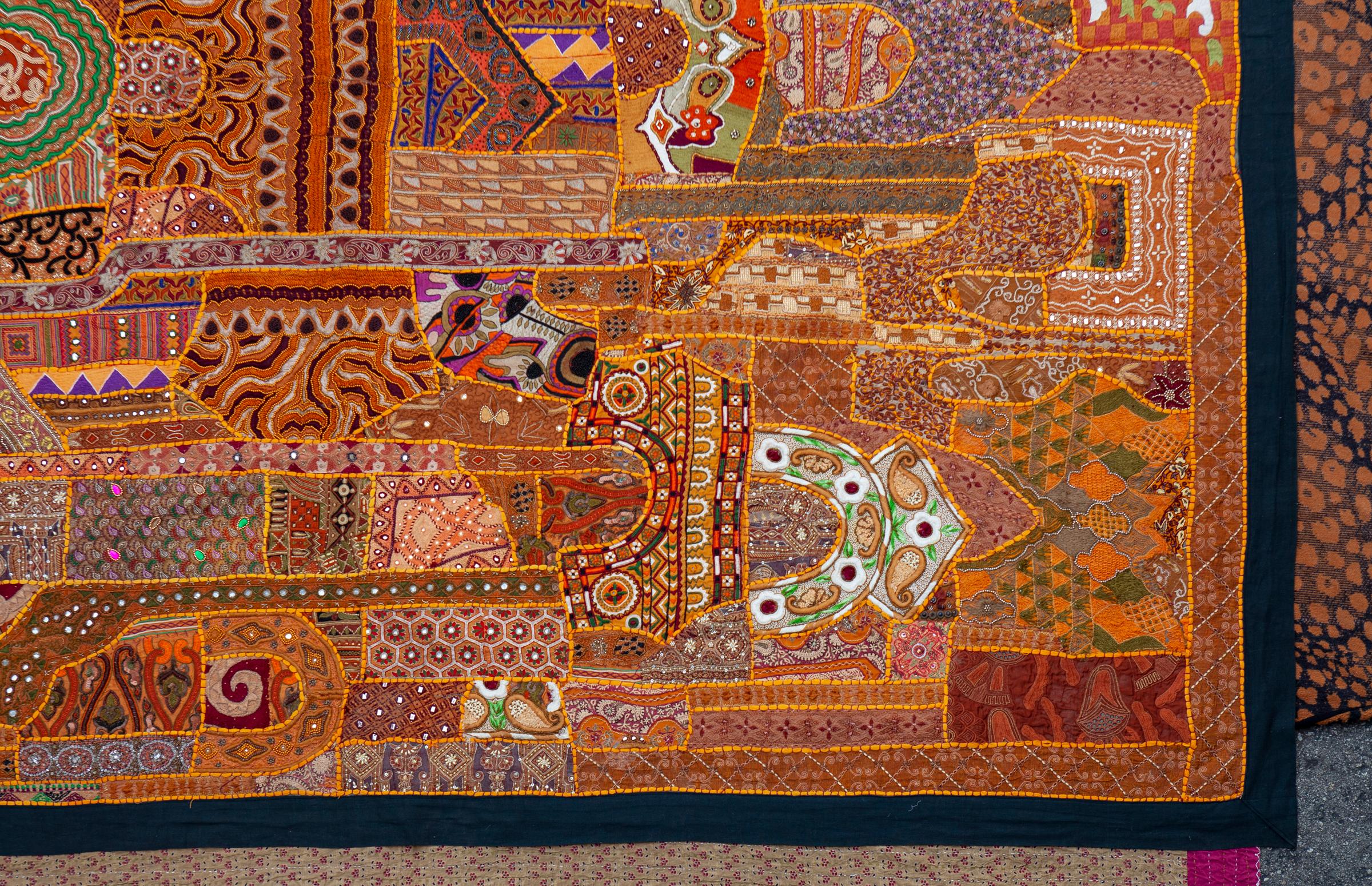 Orangefarbener ostindischer Wandbehang/Gobelin mit Pailletten. Handgefertigt mit antikem Stoff aus Indien. Einige der Stoffe stammen von antiken Saris und enthalten Glasperlen, Metallfäden und Pailletten. Abgeschlossen mit schwarzem Rand.
8'7