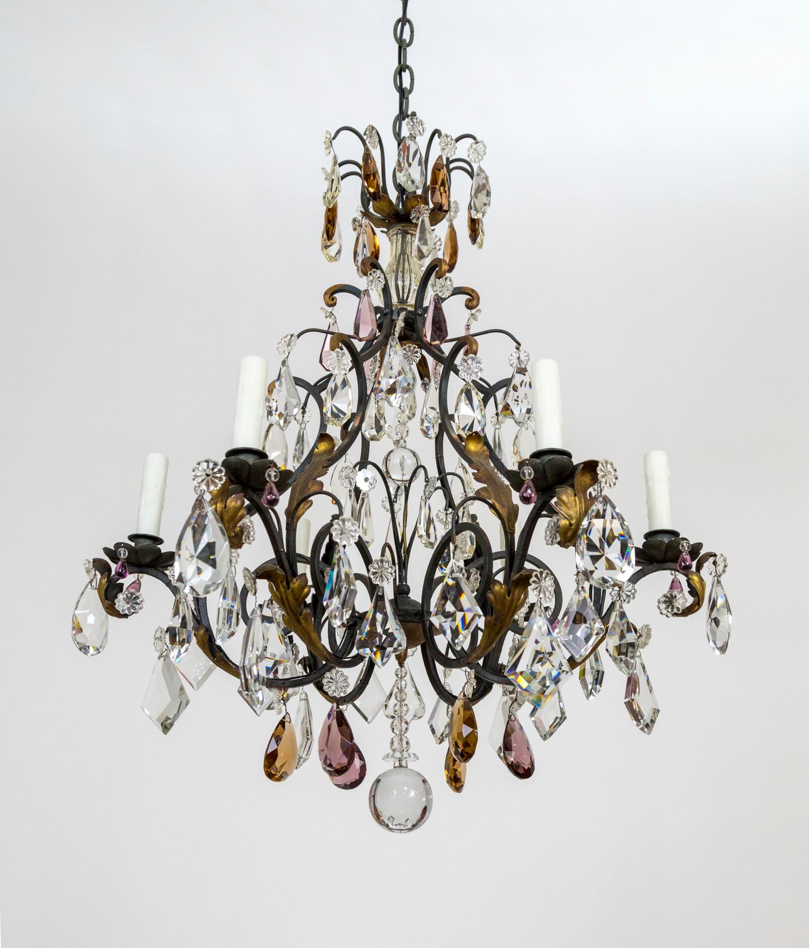 A striking chandelier in shape and color accents - including amethyst and deep amber crystals and varied metal color from brown and black to gold. With exquisite cut crystals, including large pendeloques and spires; gilt acanthus leaf accents and