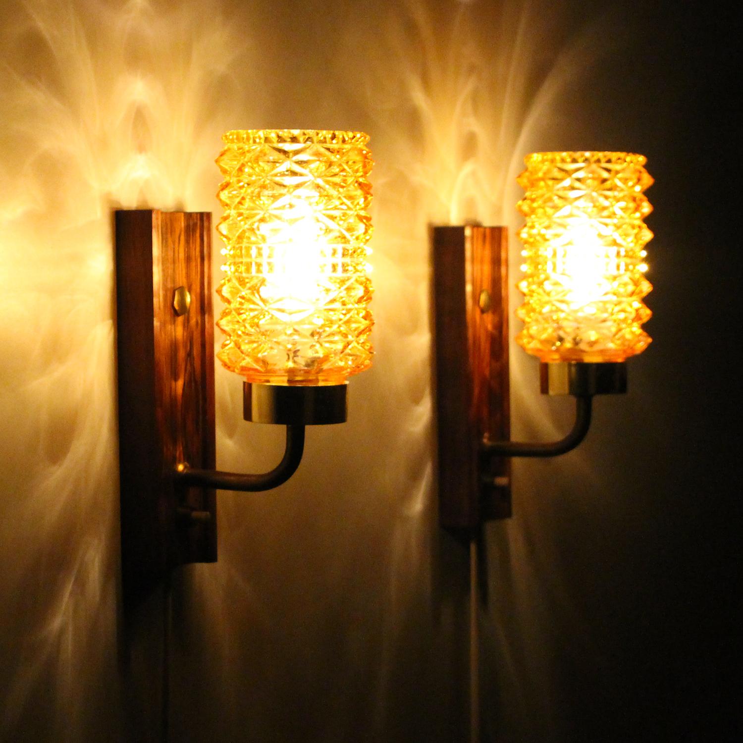 Amber & Rosewood wall lamps - 1950s Danish vintage wall lights by Danish producer Stil-lampet, all in good vintage condition.

A charming pair of midcentury sconces, each comprised of a thick cylindrical pressed glass shade, a brass lacquered