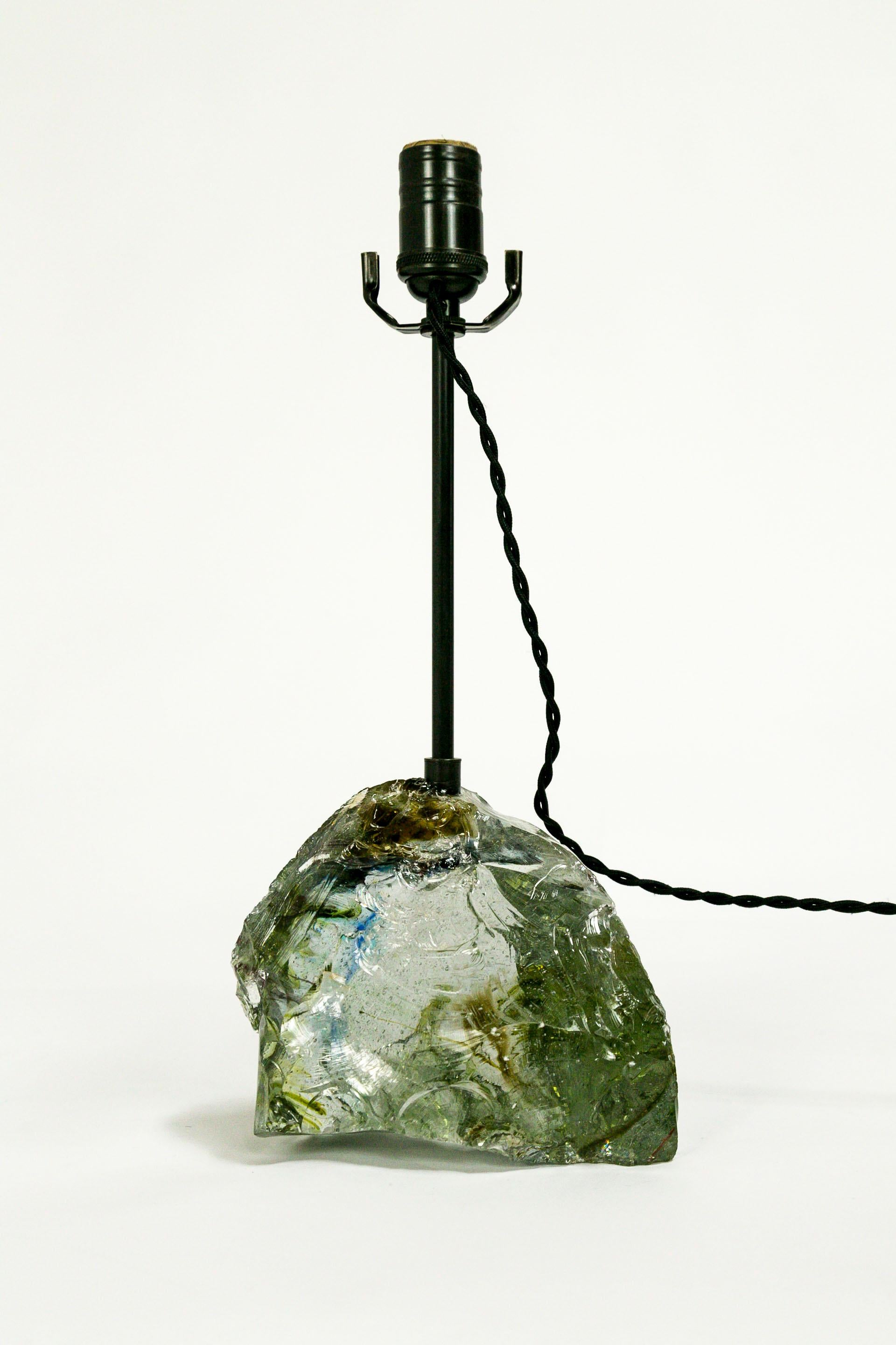 We created this French wired table lamp from a gorgeous clear, amber, blue, and sea green piece of cullet glass. It has a complex composition of color and translucency. The brass neck and socket have an oil rubbed bronze finish, with a twisted,