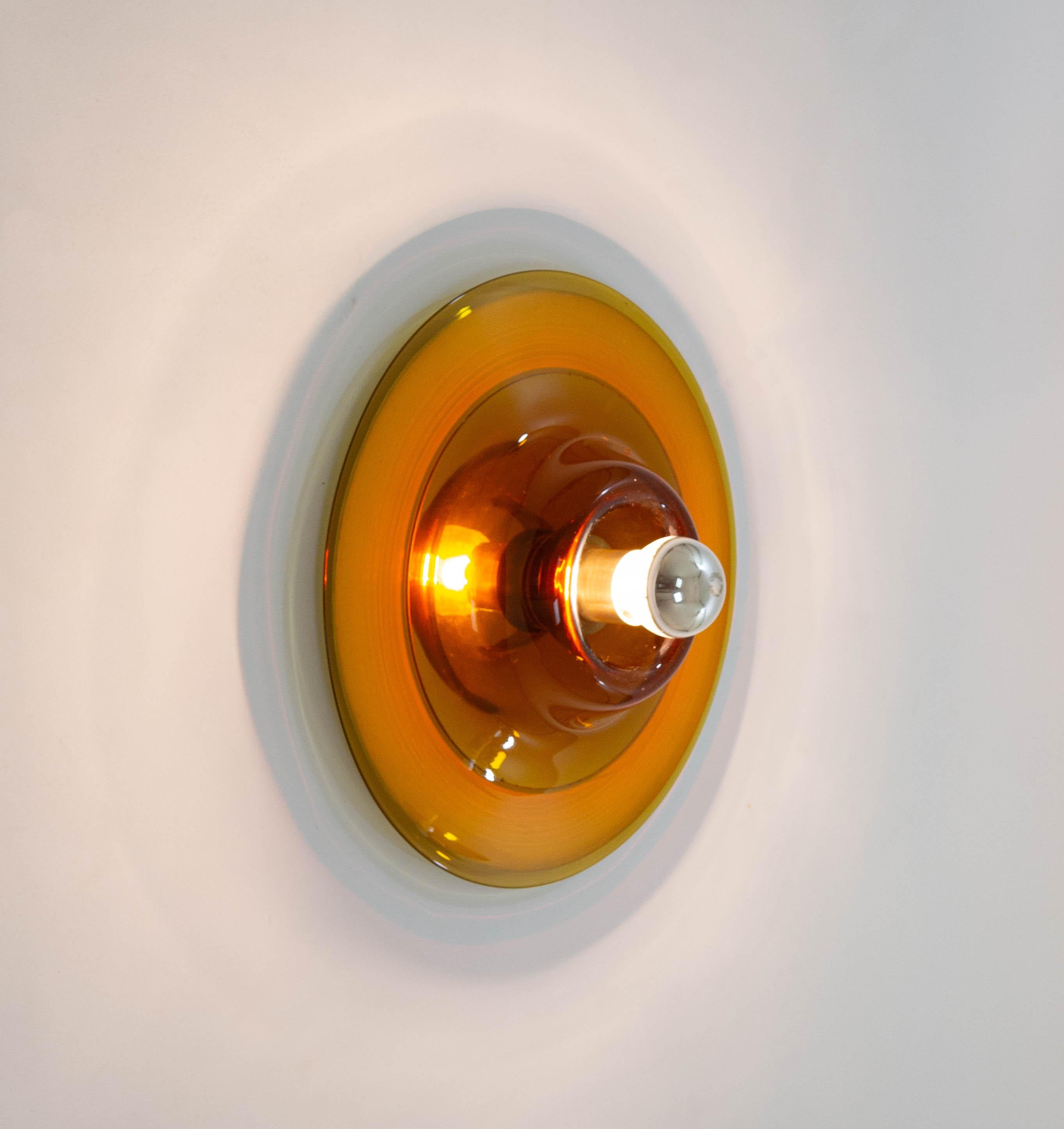No. 820 amber wall-bracket or ceiling fixture manufactured by Venetian glass specialist Venini for Pierre Cardin, 1970s.

The outer layer of the lamp is made of Murano glass which is blown and opened by hand. A small round mirror is attached to the