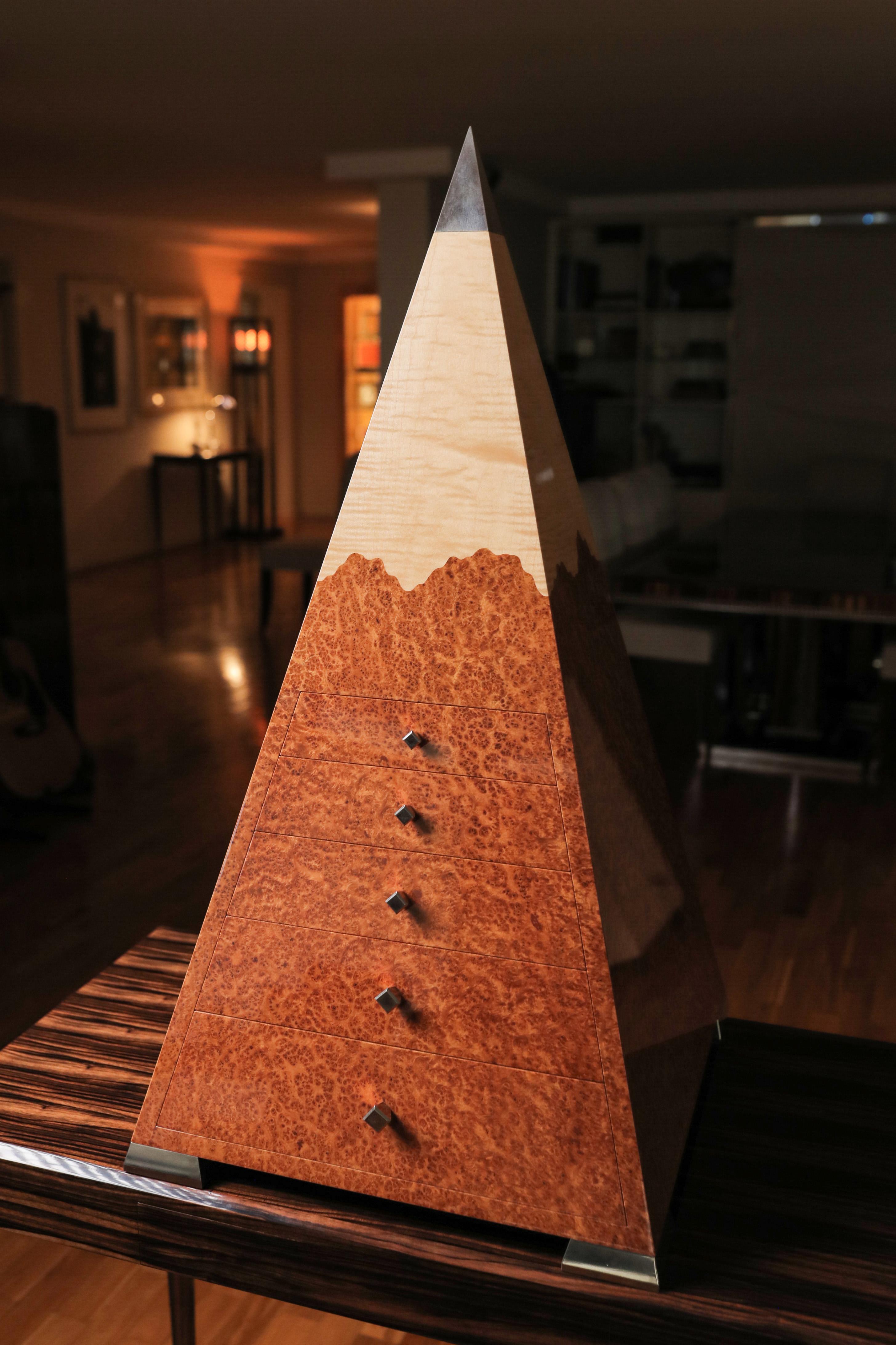 Cassettiera Amboyna Pyramid 
Il design Art Déco ha le sue origini nel periodo faraonico dell'antico Egitto. Il mistero e il fascino esotico di questo periodo iconico sono stati la nostra ispirazione per questo pezzo molto speciale. 
Una