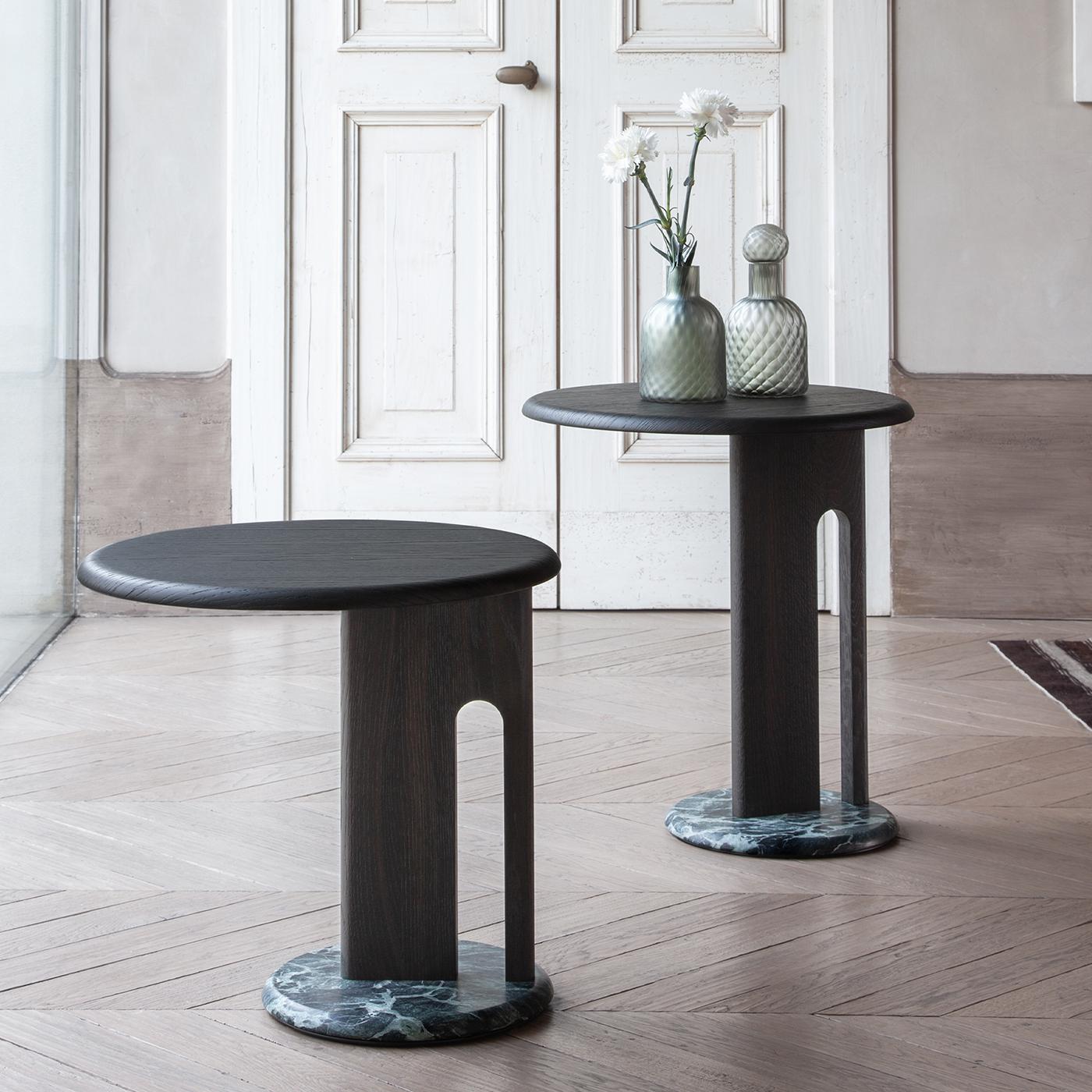 This round side table features a membrane-pressed oak veneer top with a refined lagoon finish. The structure is crafted from solid turned oak supporting a sturdy circular base made of authentic green alpine marble, combining natural elegance with