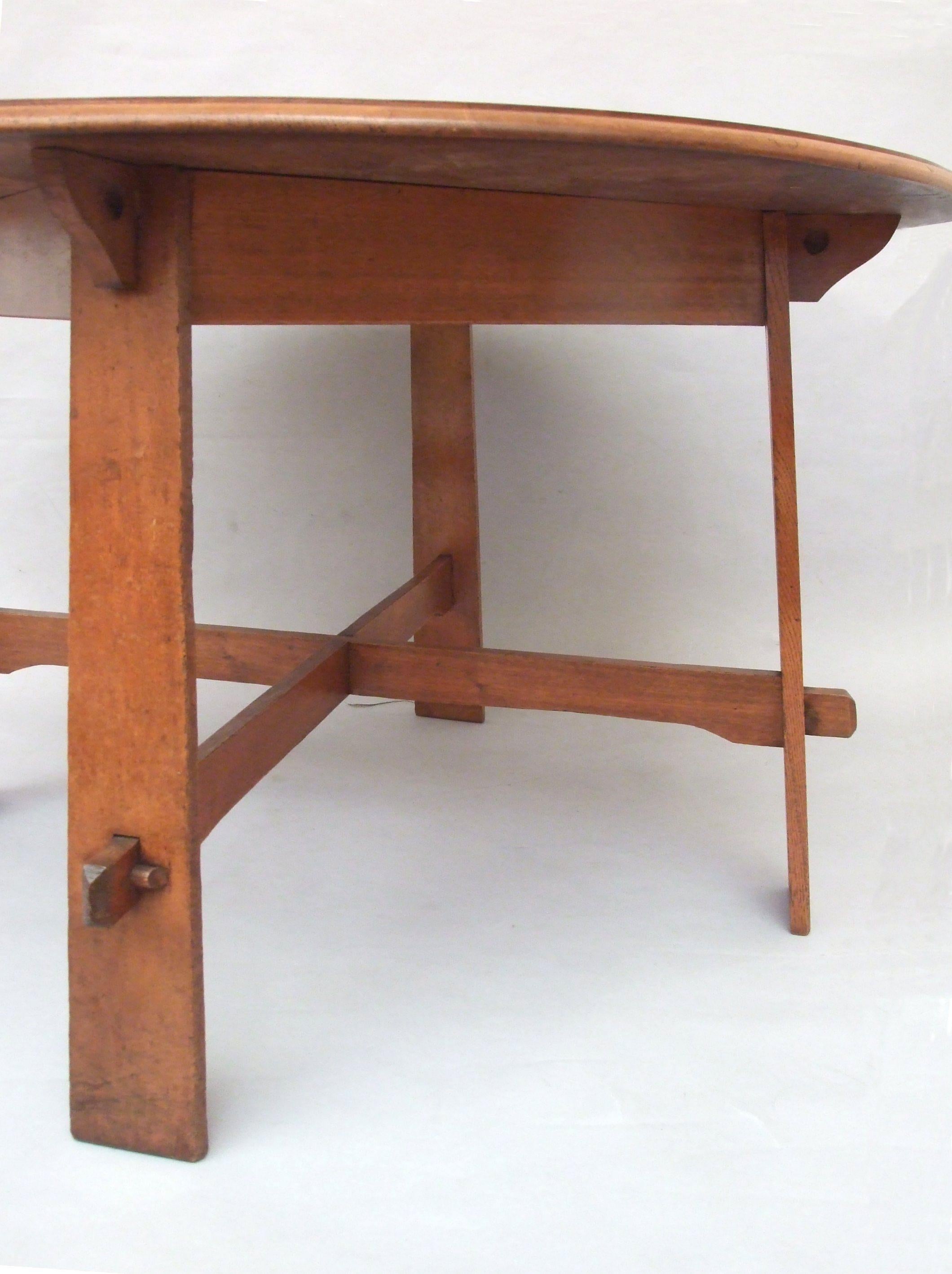 Ambrose Heal an oak, Arts & Crafts, round dining table, molded edge and bracket supports to the table top, four tapering 'plank' legs, with pegged cross-stretchers, 'No 8' in Heal's archive, designed by Ambrose Heal, first produced in 1908, circa