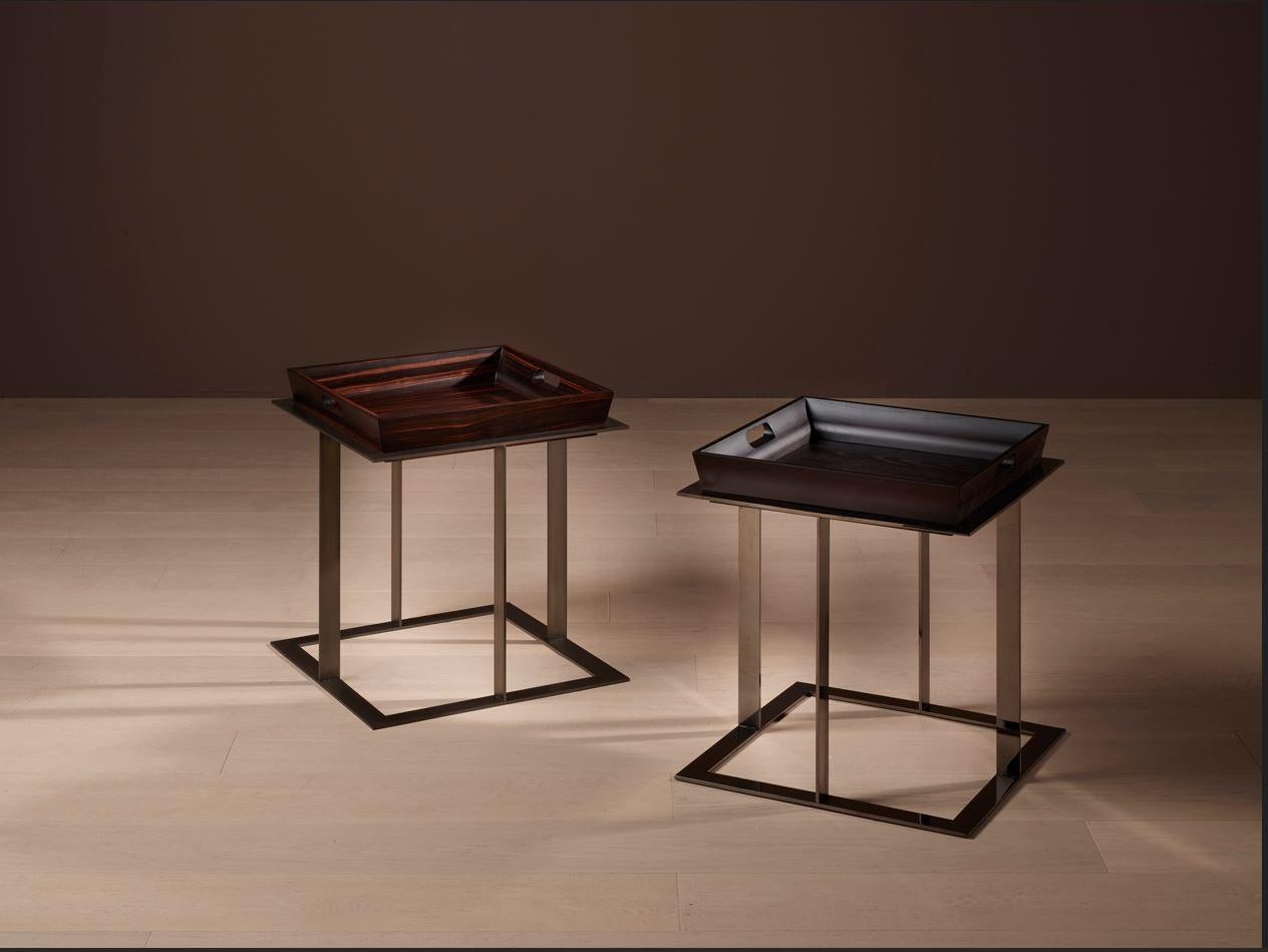 La table d'appoint AMBROSS est un exemple exceptionnel de luxe et de maîtrise artisanale. Le plateau amovible en ébène mat est soutenu par un socle en bronze antique. Le plateau est également disponible dans une variante en frêne teinté moka, qui se