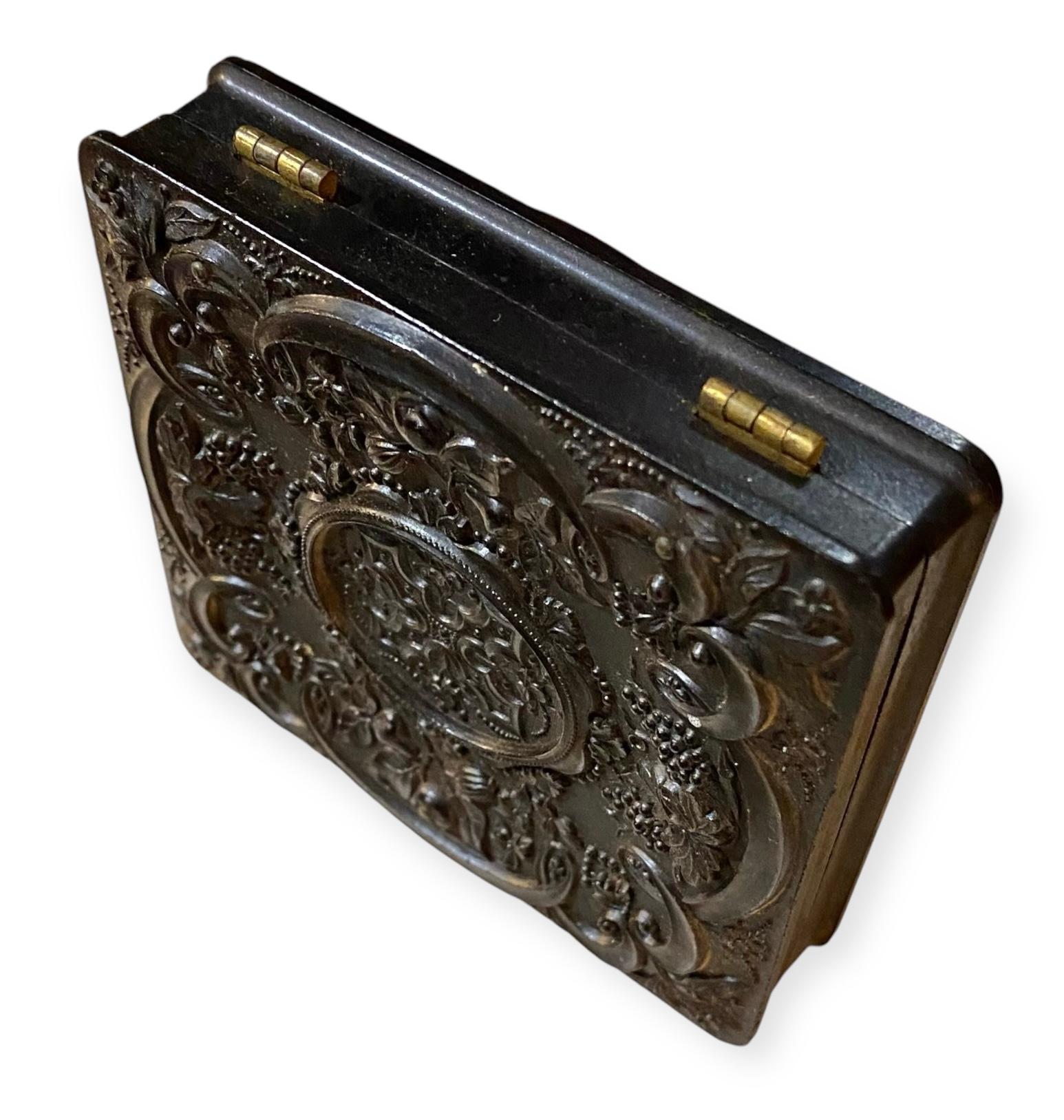 Idéntico por delante y por detrás, este estuche de gutapercha marrón tiene un precioso diseño floral con mínimos dibujos geométricos. El marco interior de latón dorado estampado y el paspartú interior están en buen estado, firmemente colocados en el