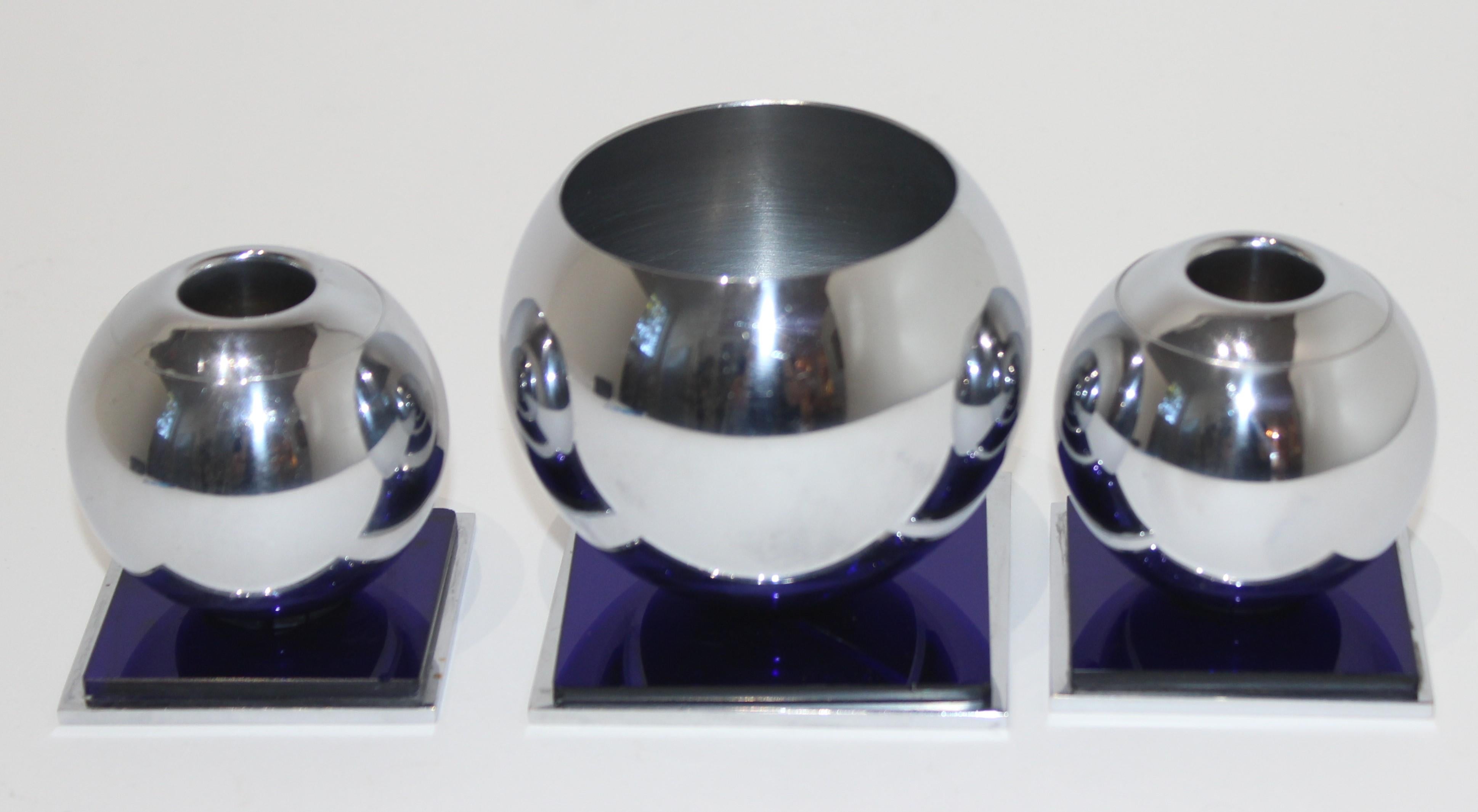 This stylish and chic three-piece American Art Deco cobalt blue and chrome candleholder and vase date to the 1930s and were created by Russel Wright for Chase USA 

Note: The height of the vase is 3.14