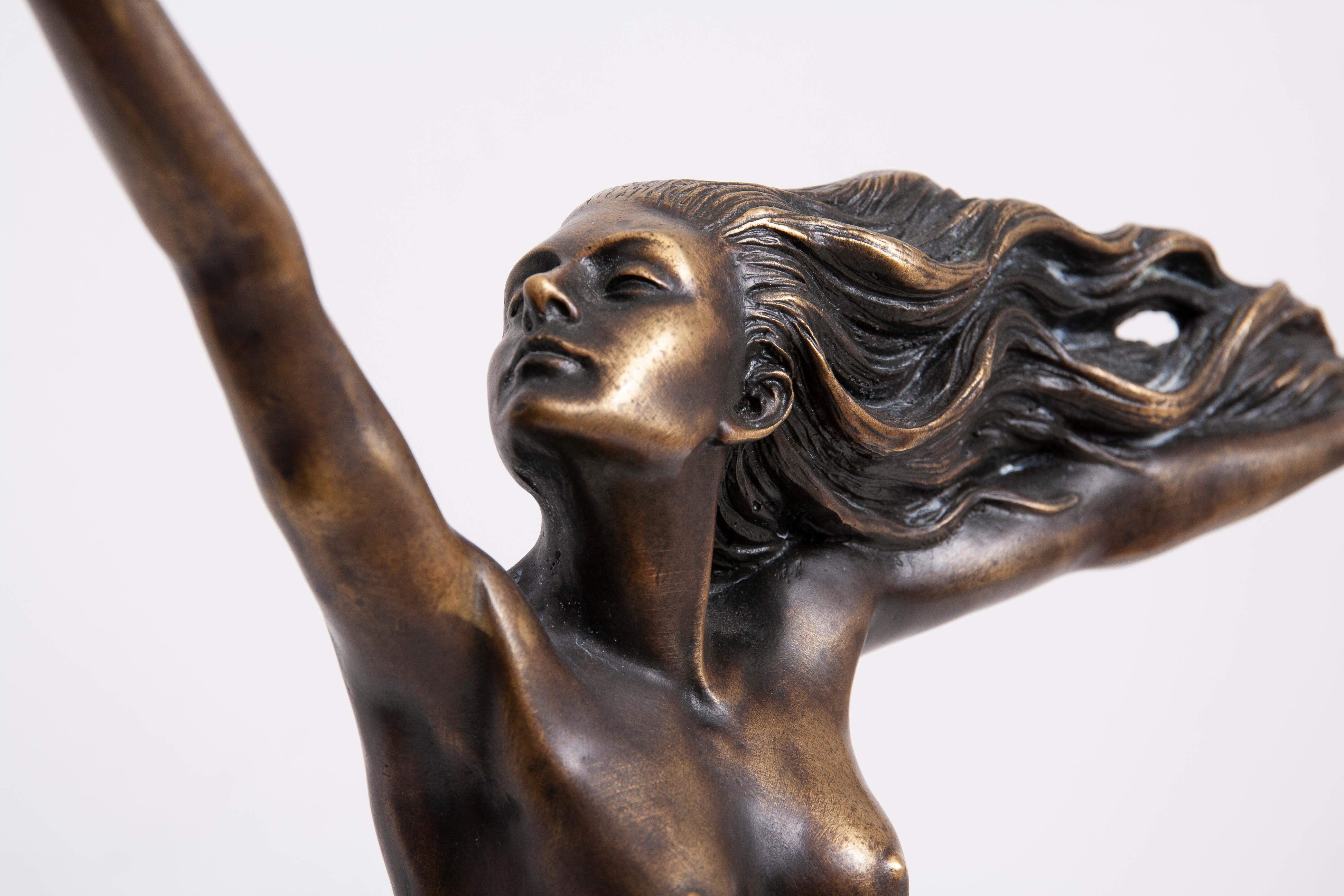 Die Art-déco-Bronze von Amedeo Gennarelli zeigt eine unbekleidete Dame, die fast kerzengerade und sittsam auf einer hohen Marmorsäule sitzt. Die nackte Frau hebt ihren rechten Arm so hoch wie möglich, um der Taube, die auf ihrer rechten Hand sitzt,