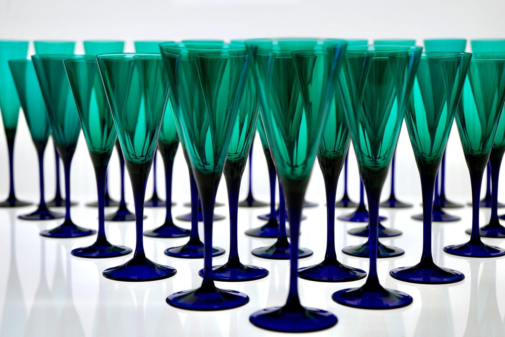 A complete ensemble of thirty-six mouth-blown glasses, comprising twelve flutes, twelve wine glasses, and twelve water goblets. Each piece is executed in transparent Murano glass, with a chromatic transition from deep cobalt blue at the base to a