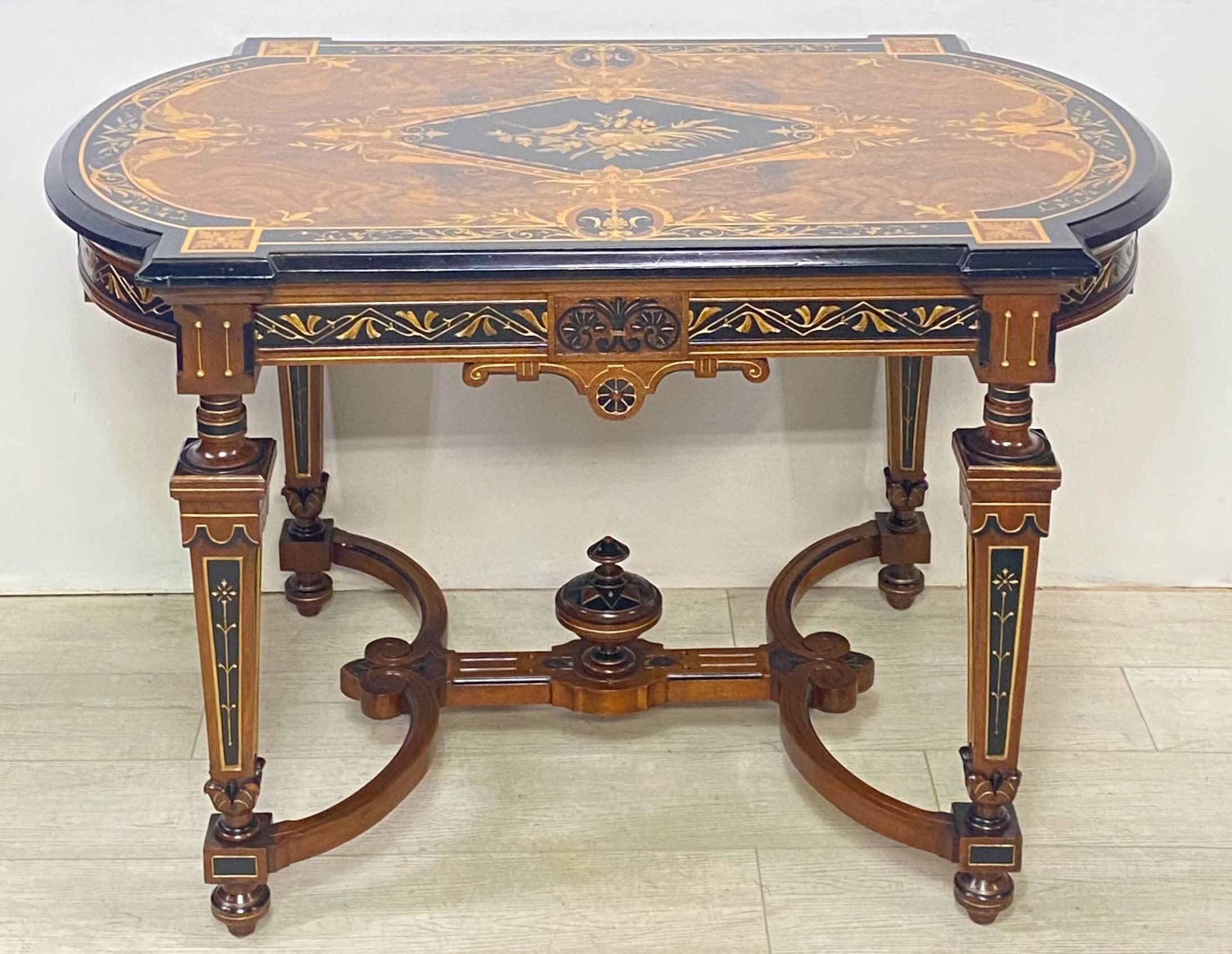 Table centrale victorienne en marqueterie de noyer dans le style de Herter Brothers, New York, vers 1880. 
Le plateau elliptique partiellement doré et ébonisé à bord mouluré renferme une scène centrale encadrée et très détaillée d'un oiseau et de